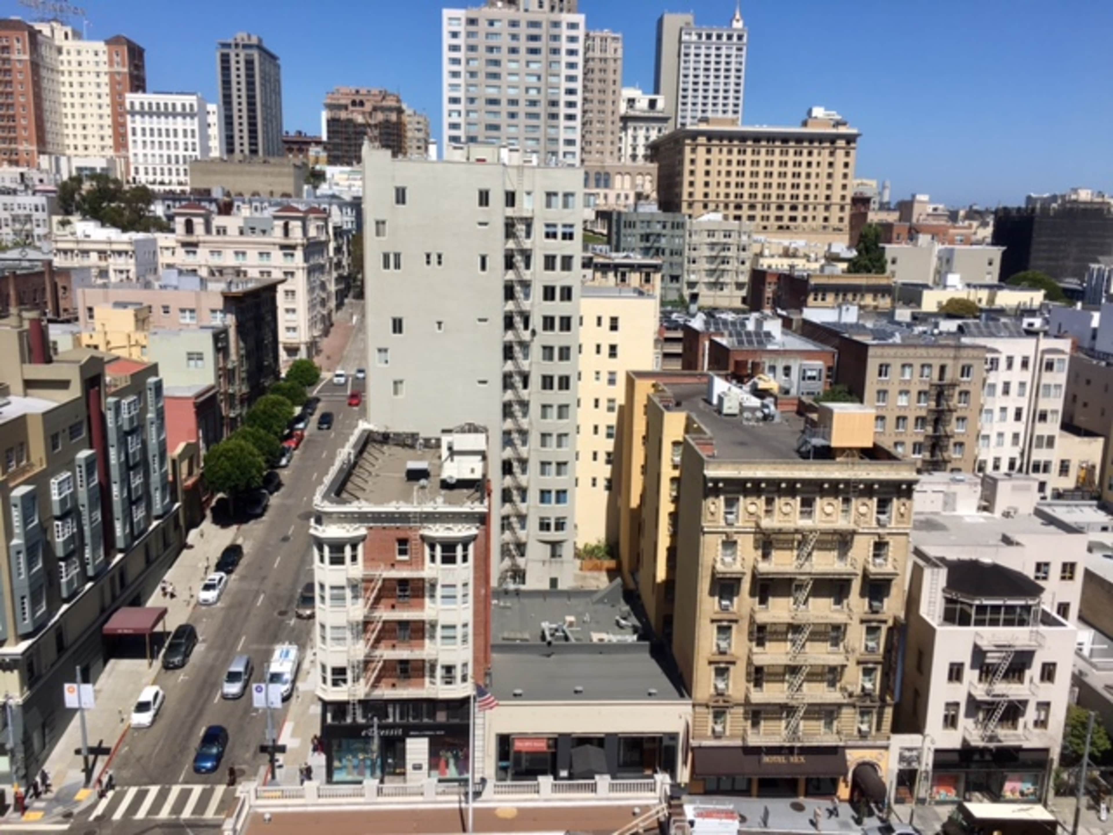 A densely populated urban skyline featuring high-rise buildings and a street lined with lower-rise structures.