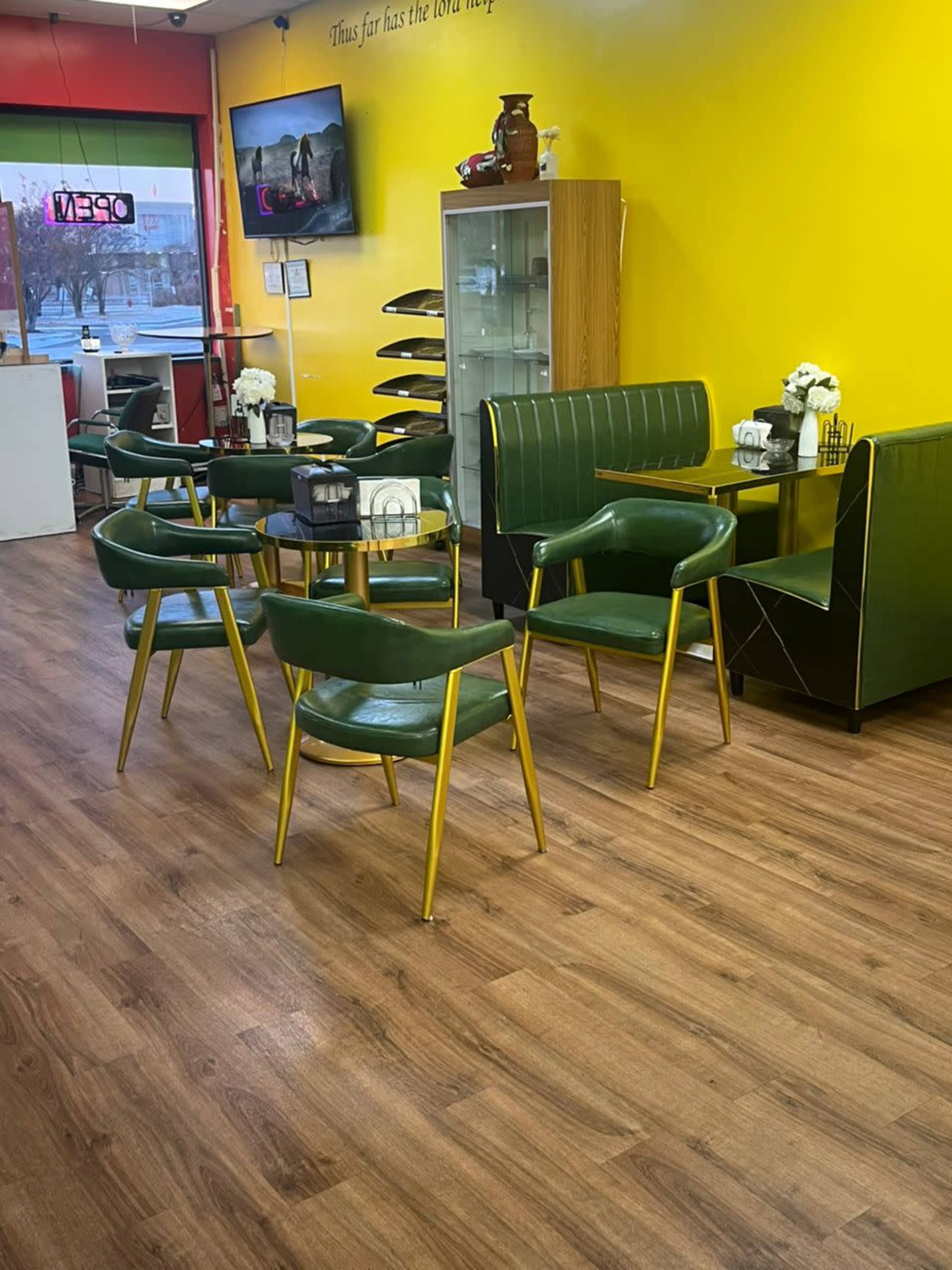 The image shows a brightly colored interior of a cafe, featuring green chairs with gold legs and wooden flooring.