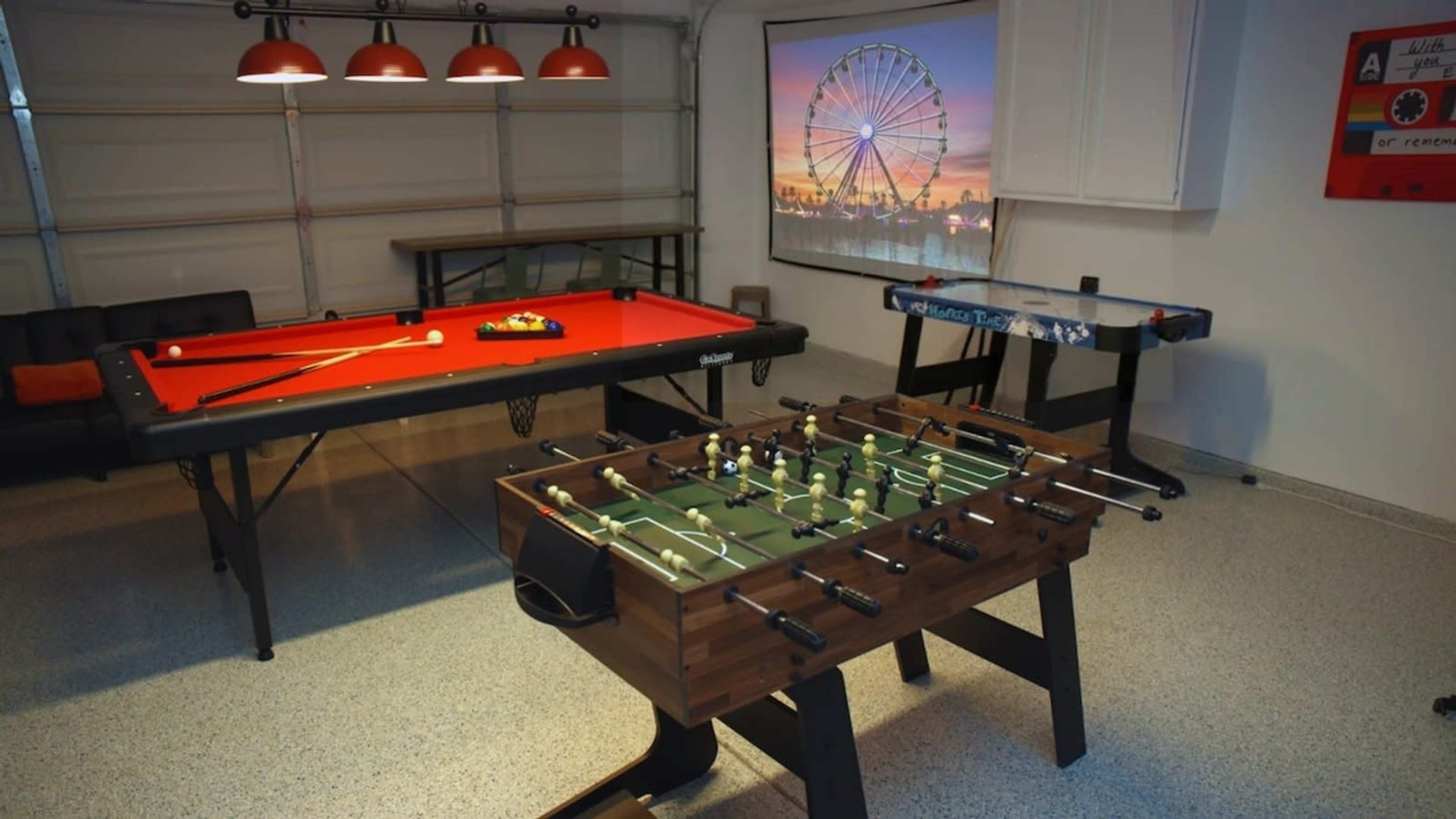 The image shows a recreational room with a pool table, a foosball table, and a screen displaying a ferris wheel.