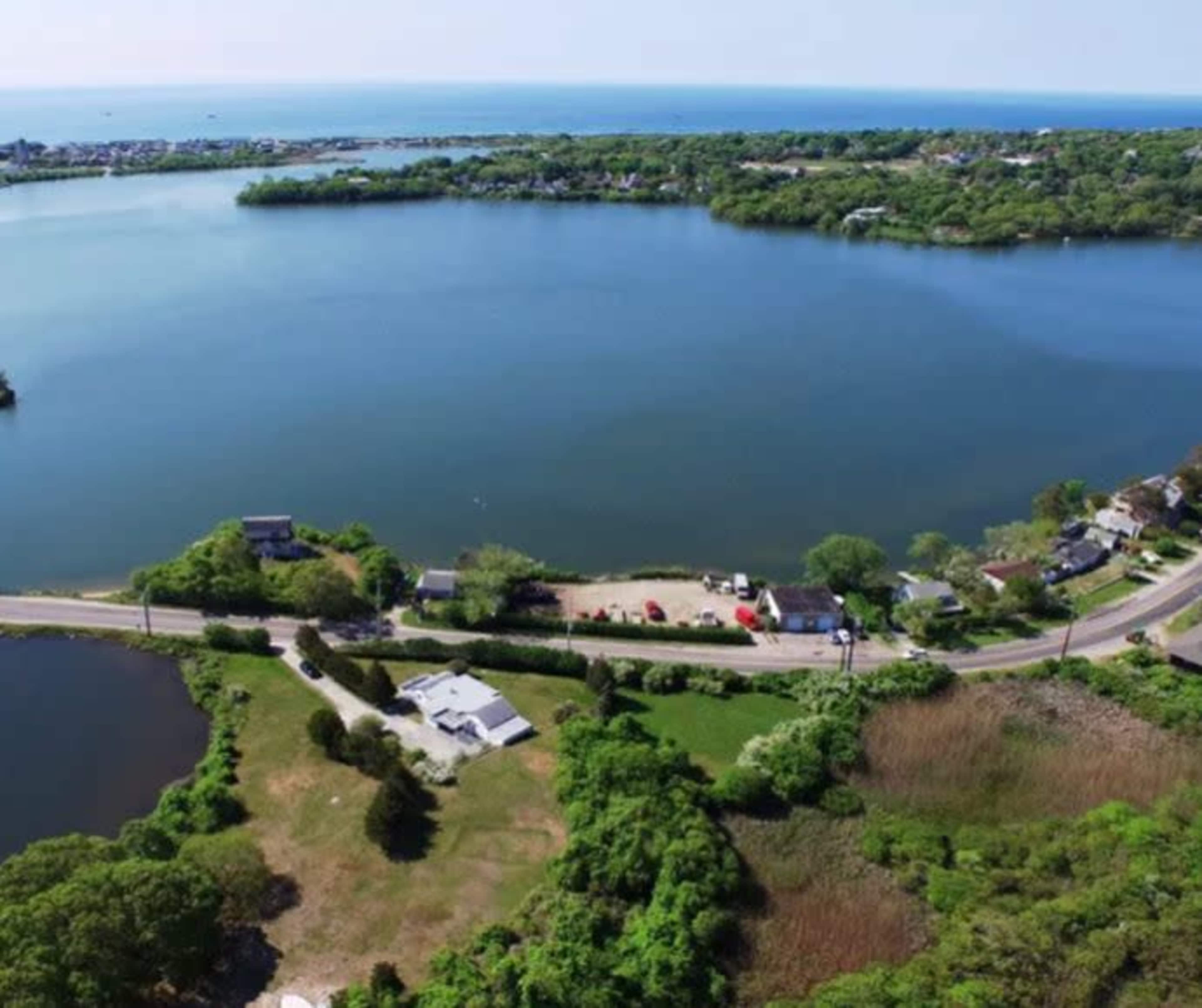 A coastal landscape with a bay, green vegetation, and houses along the shoreline.
