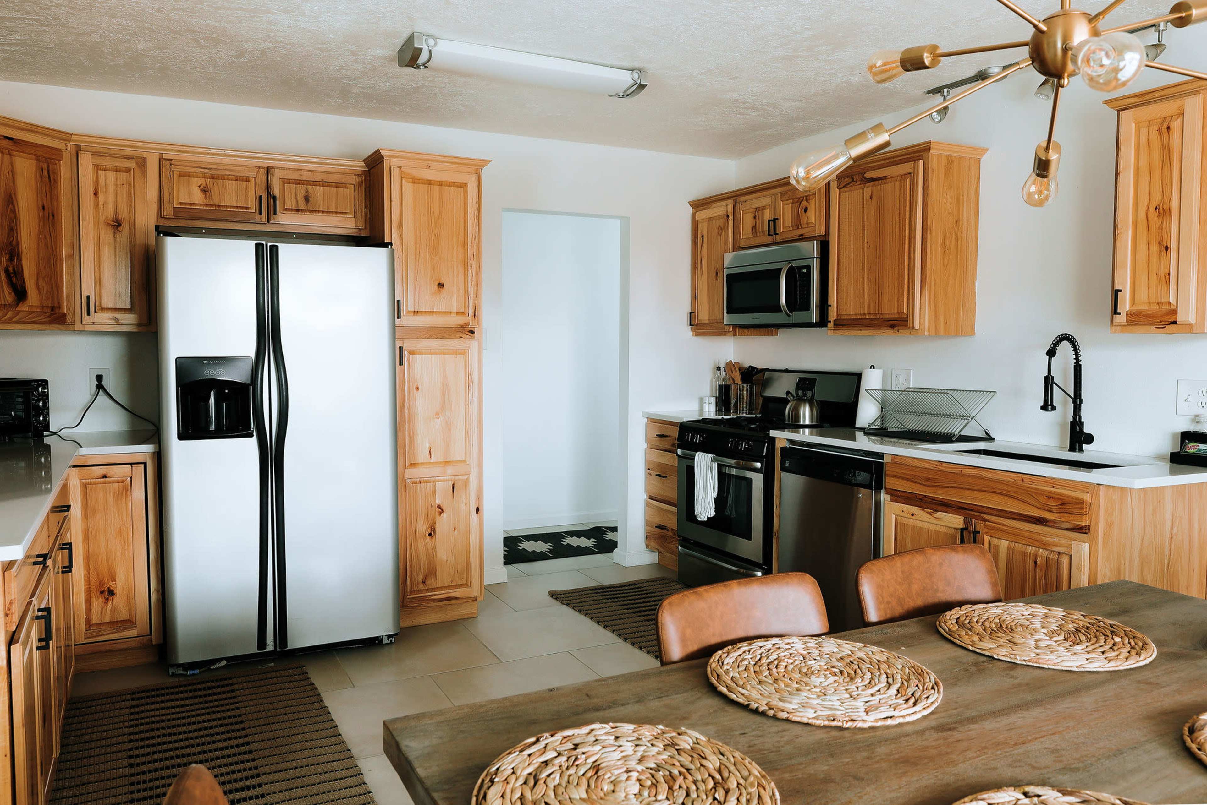 A modern kitchen with wooden cabinetry, stainless steel appliances, and a dining table set with woven placemats.