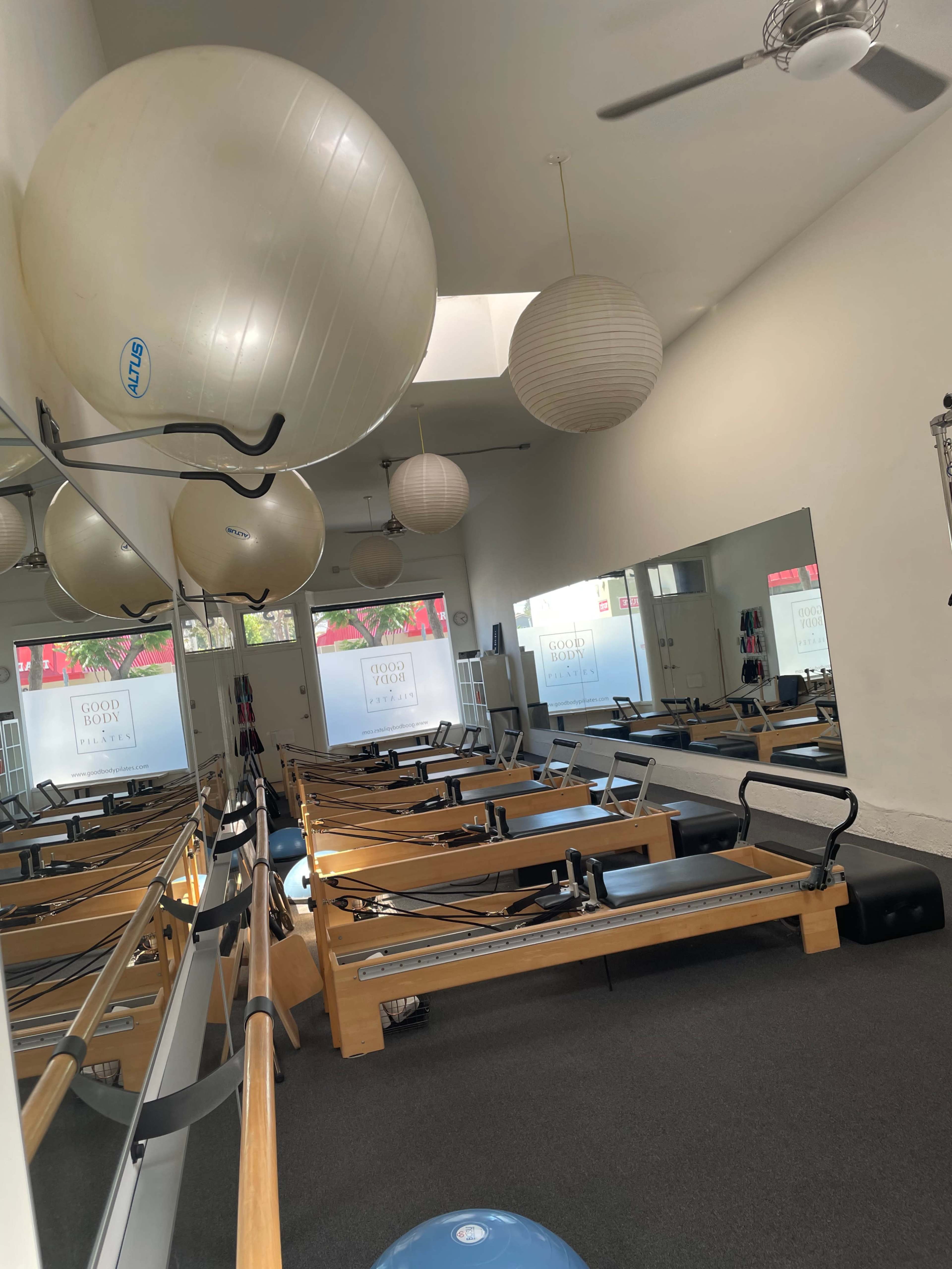 A fitness studio equipped with reformer machines, exercise balls, and paper lanterns hanging from the ceiling.