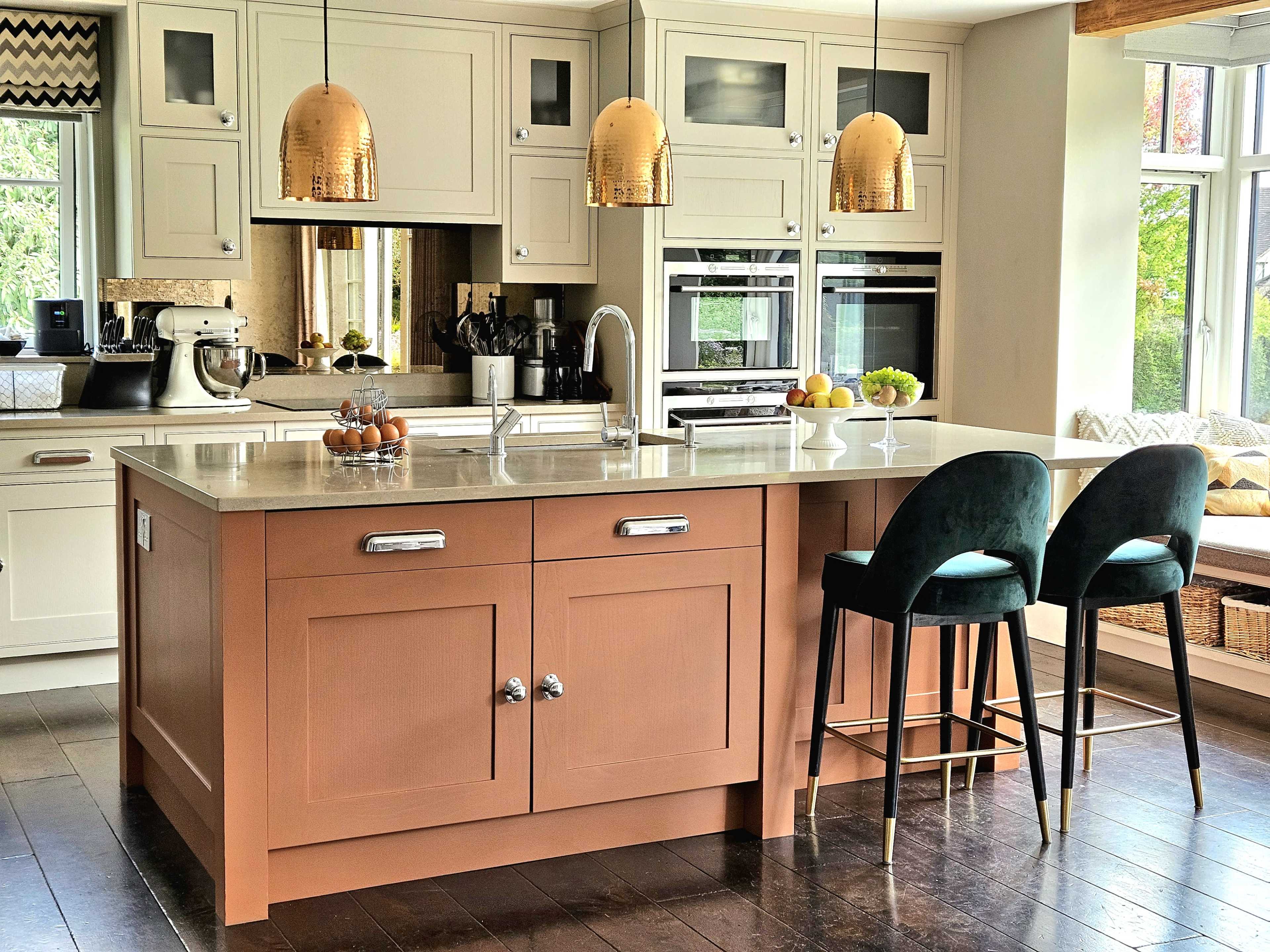 The image shows a modern kitchen featuring an island with a brownish-orange base, topped with a light-colored countertop, and three pendant lights hanging above it.