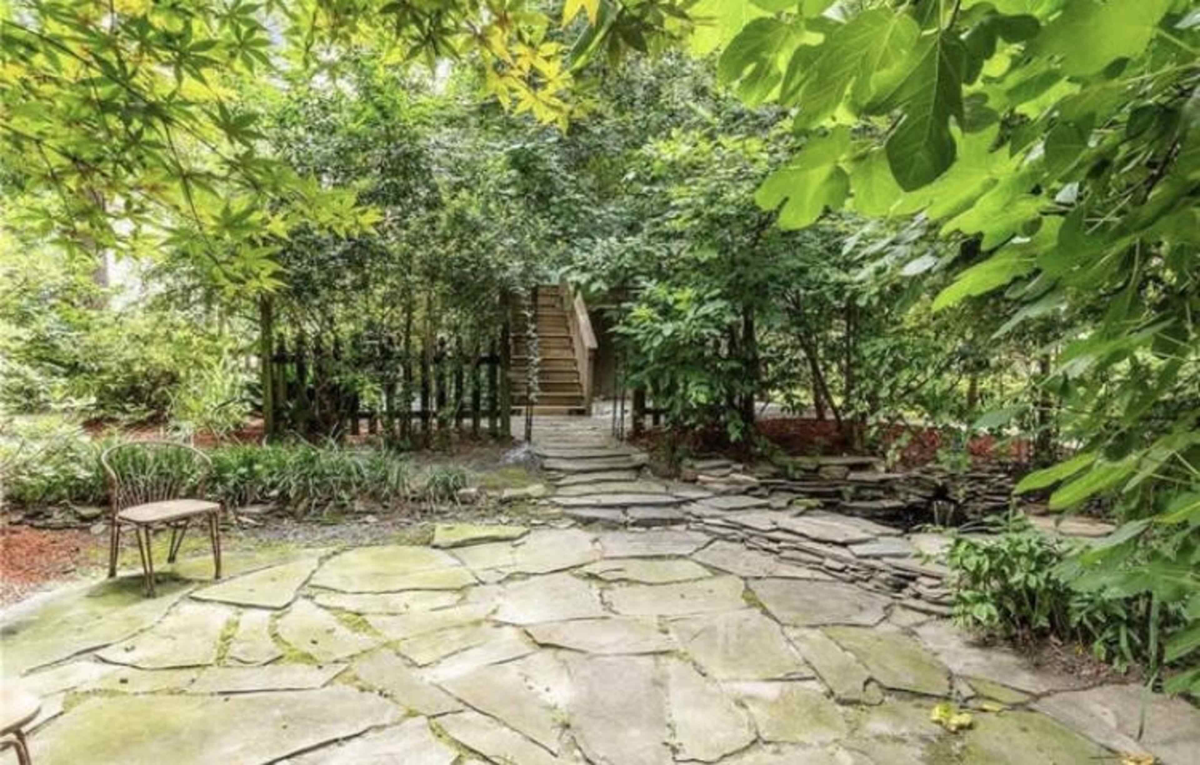 A stone pathway leading to wooden steps surrounded by lush greenery and plants.