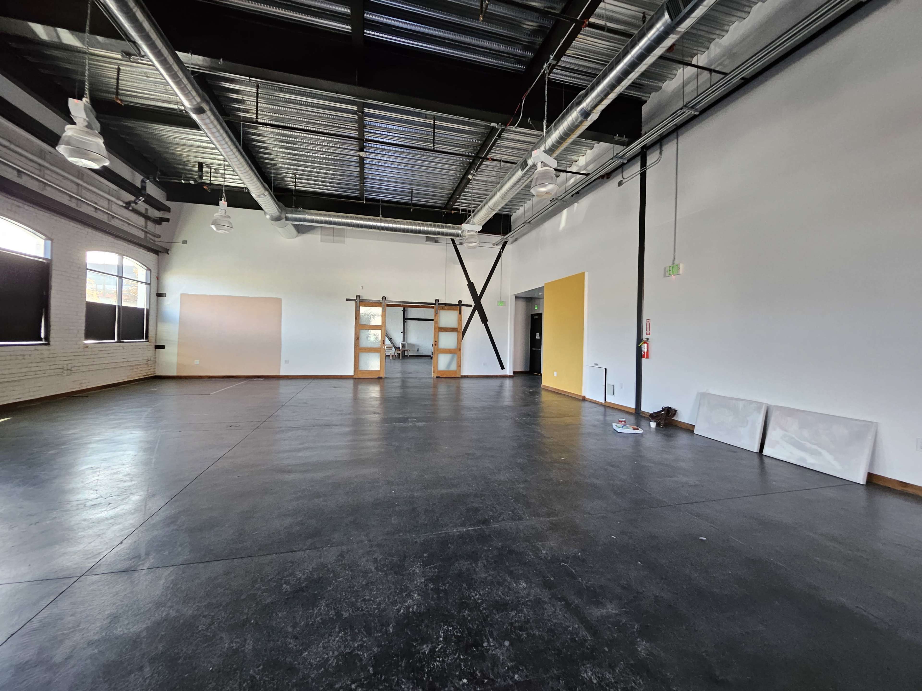 A spacious, empty interior with polished concrete flooring, large windows, and minimal furnishings.