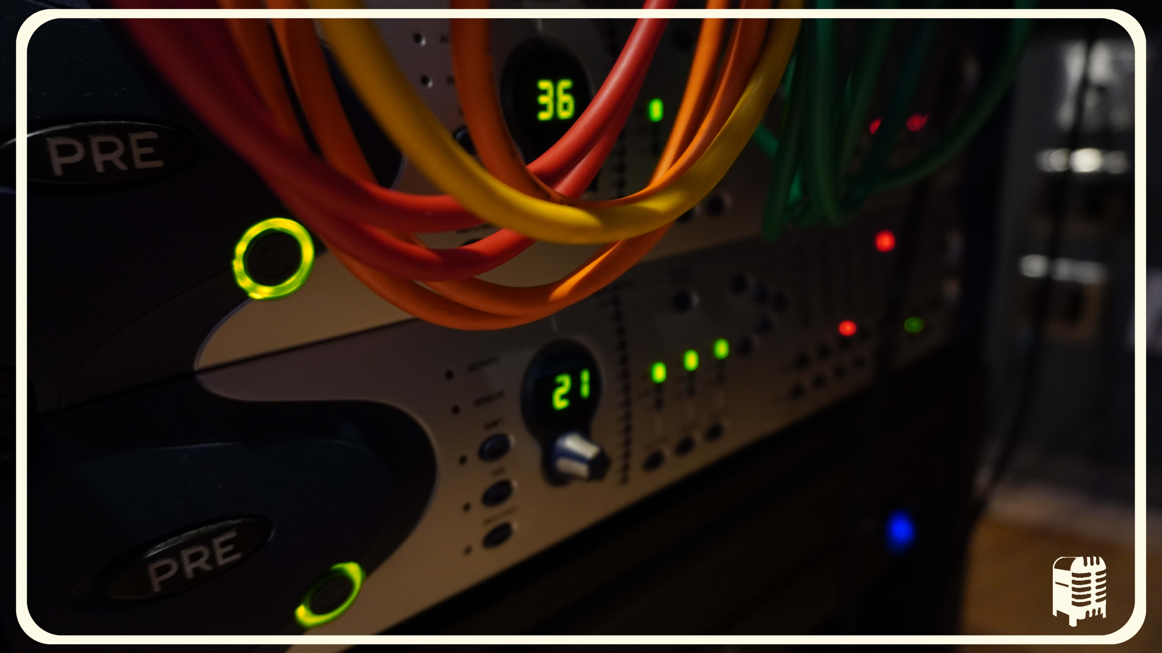 The image shows a close-up of audio equipment with colorful cables and lights indicating operational status.