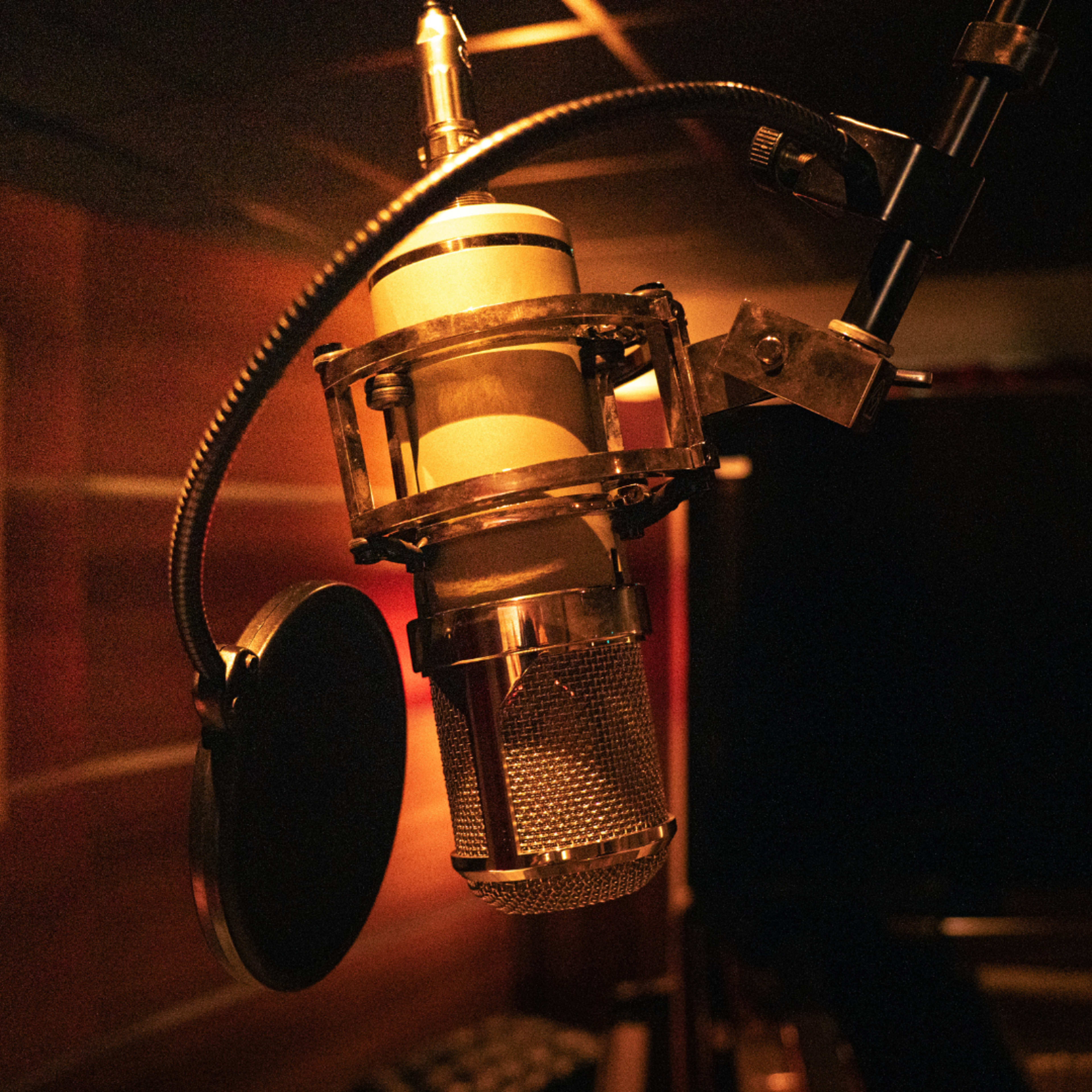 A vintage microphone is suspended in a dimly lit recording studio.