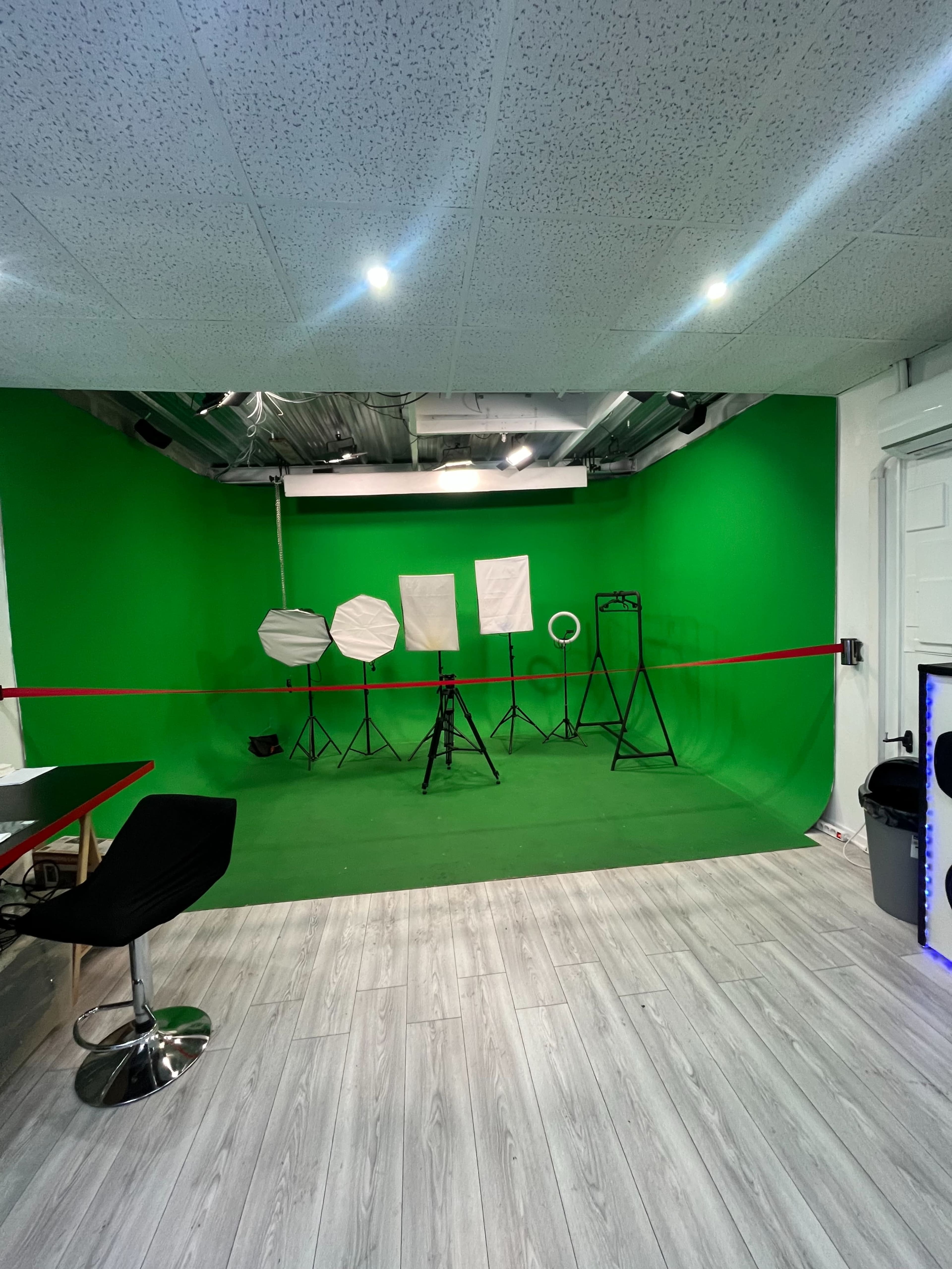 A green screen studio with various lighting equipment arranged in front of a green backdrop.