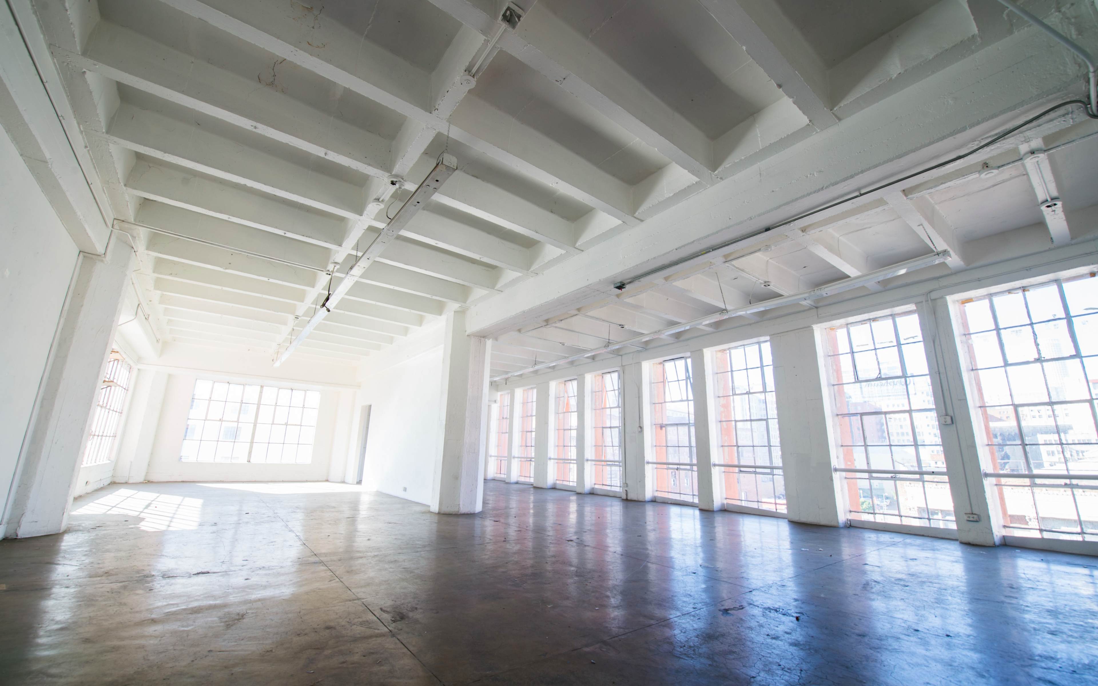 A spacious, empty room with large windows and a high ceiling.