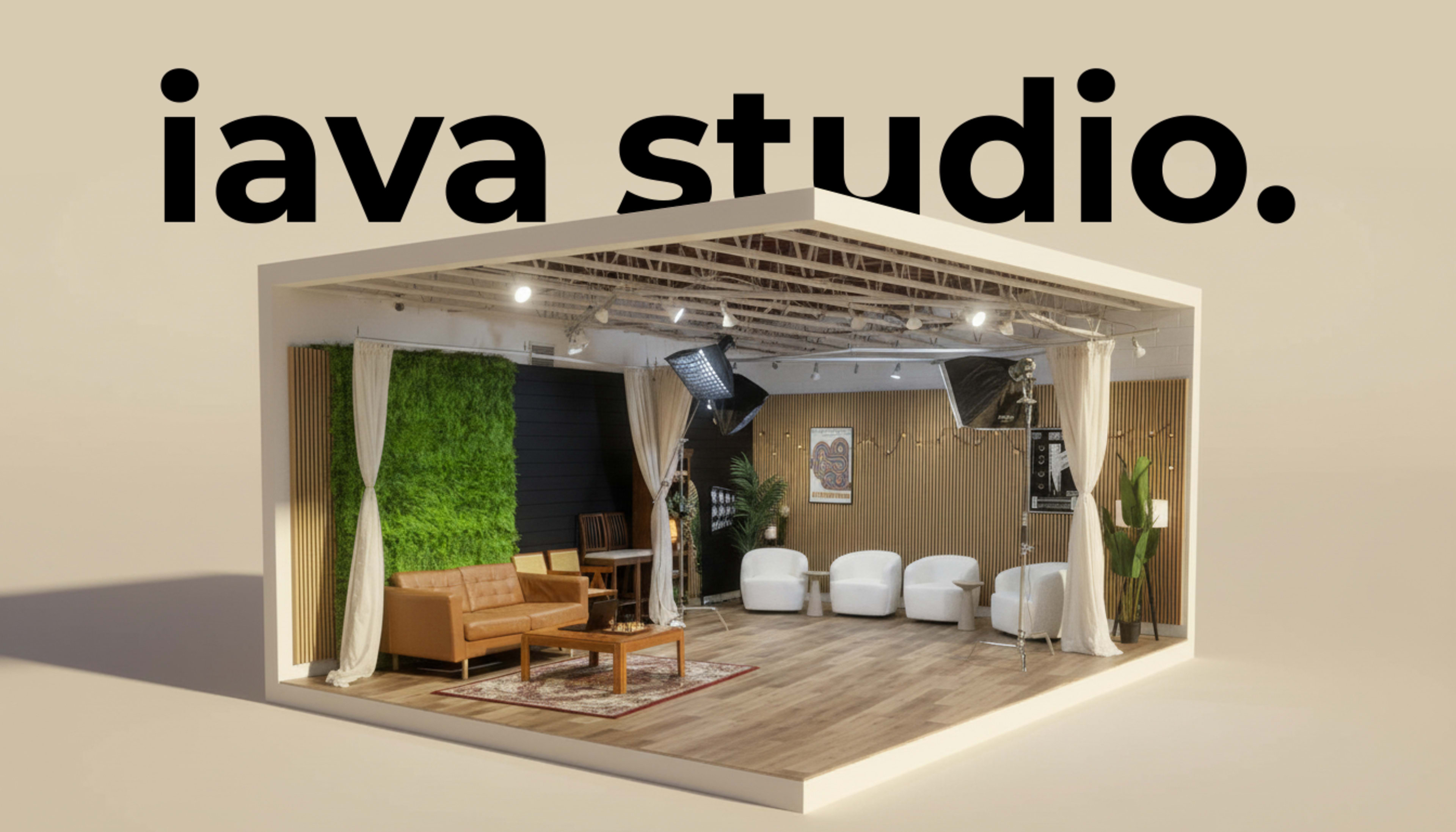 The image depicts a modern studio space featuring a wooden floor, a green wall, a brown sofa, white chairs, and various lighting equipment.