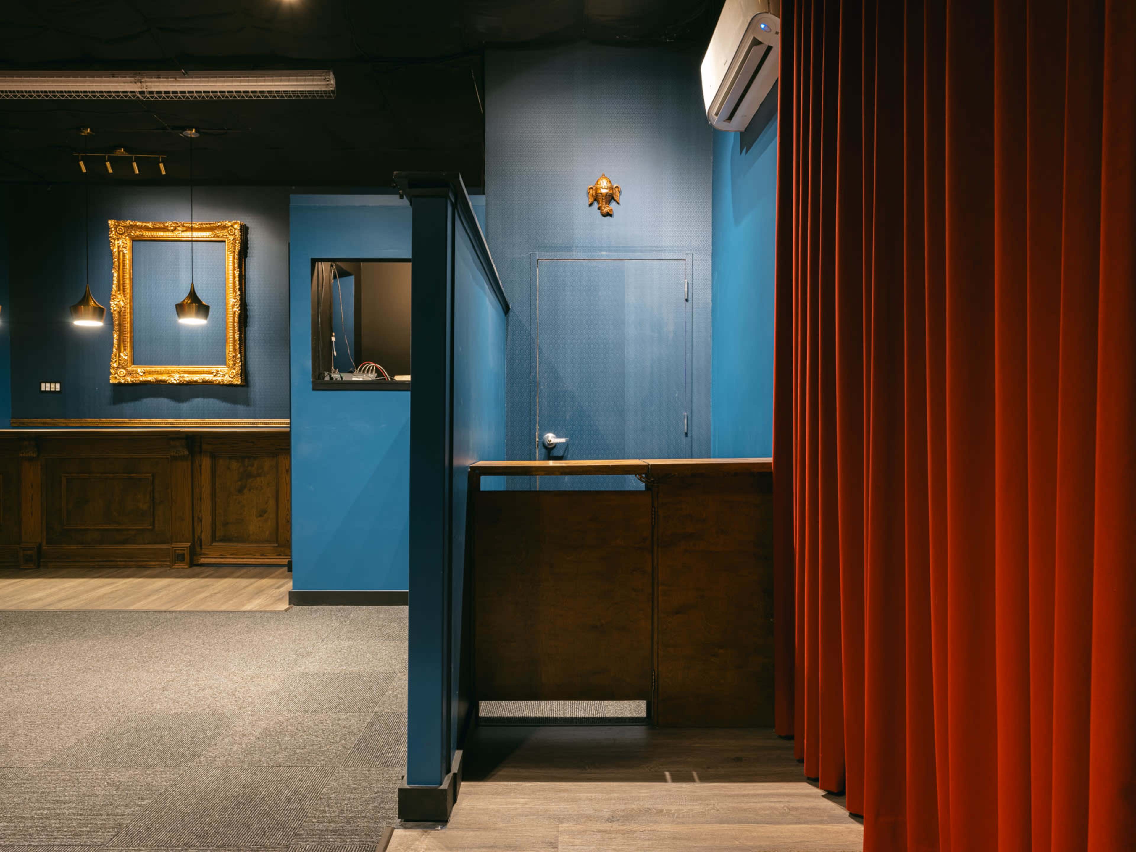 A room with a blue wall, a wooden counter, a red curtain, and decorative elements including a gold framed mirror on the wall.