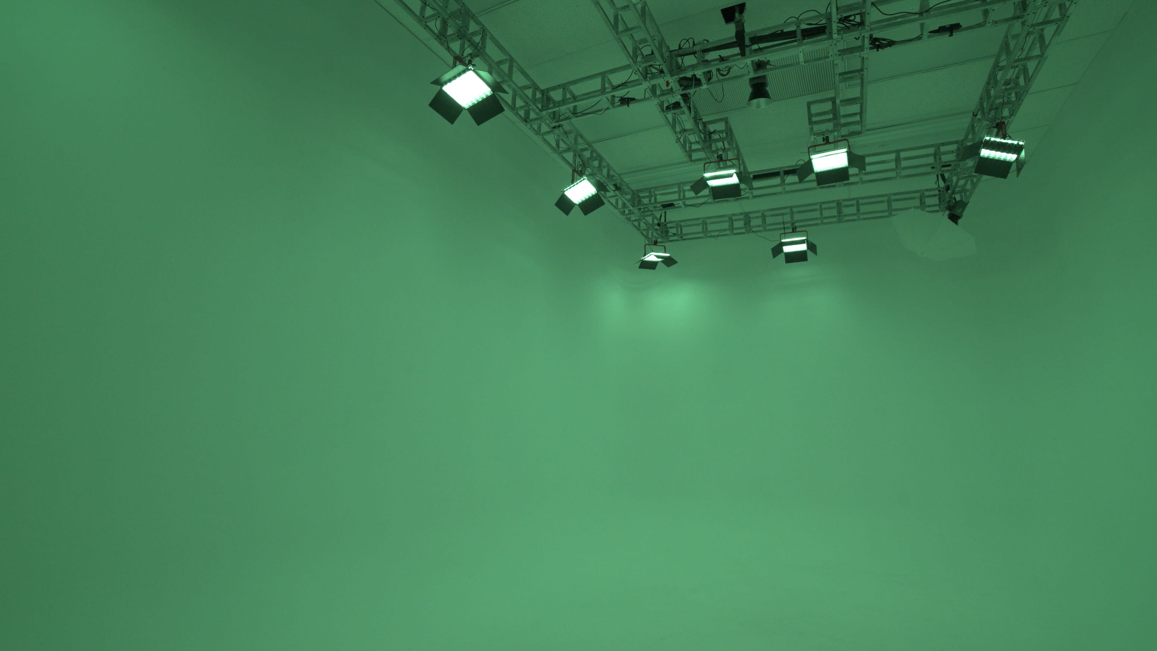 A green screen studio with overhead lighting fixtures.