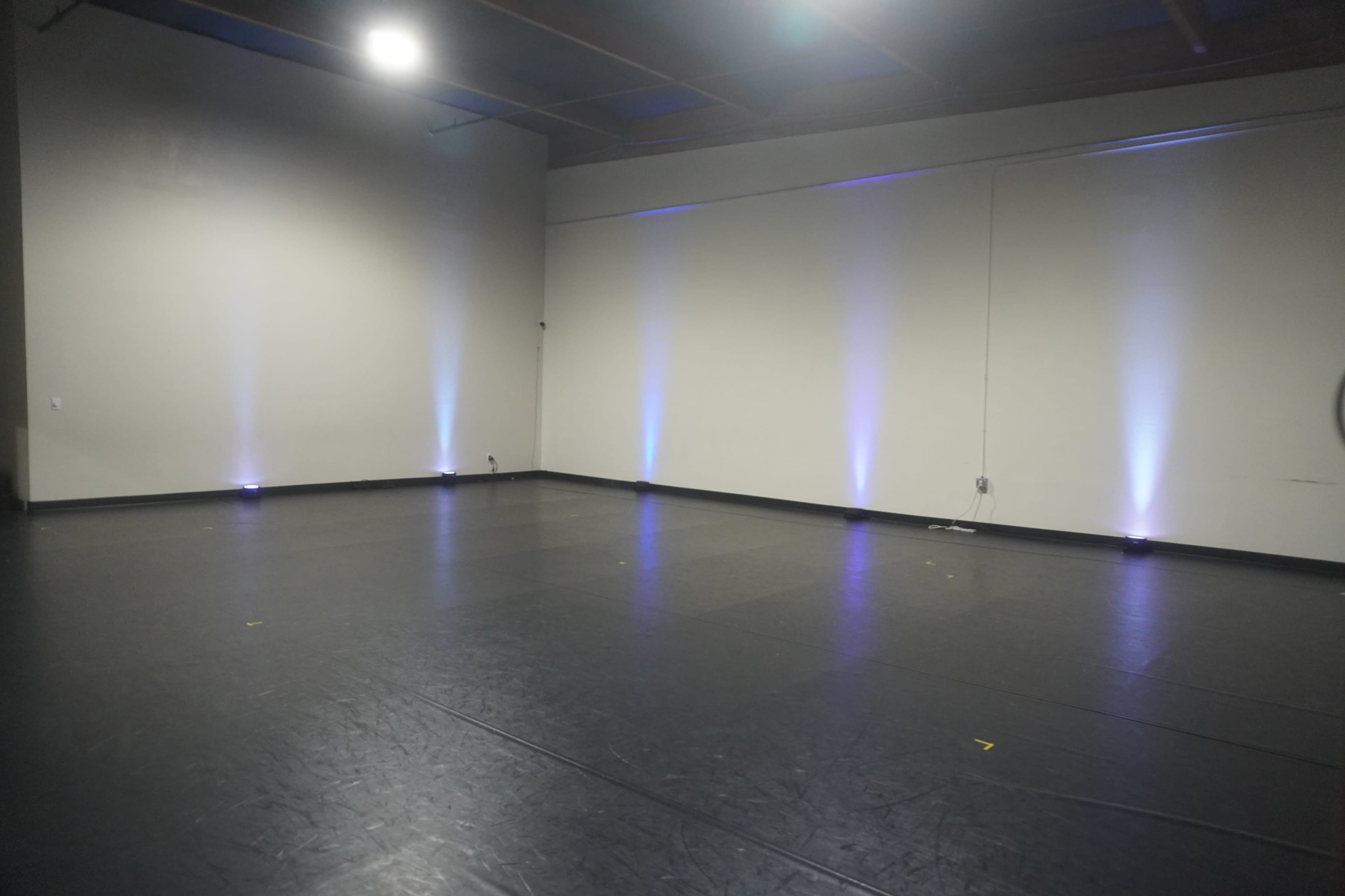 A spacious studio featuring a dark floor and softly illuminated walls.