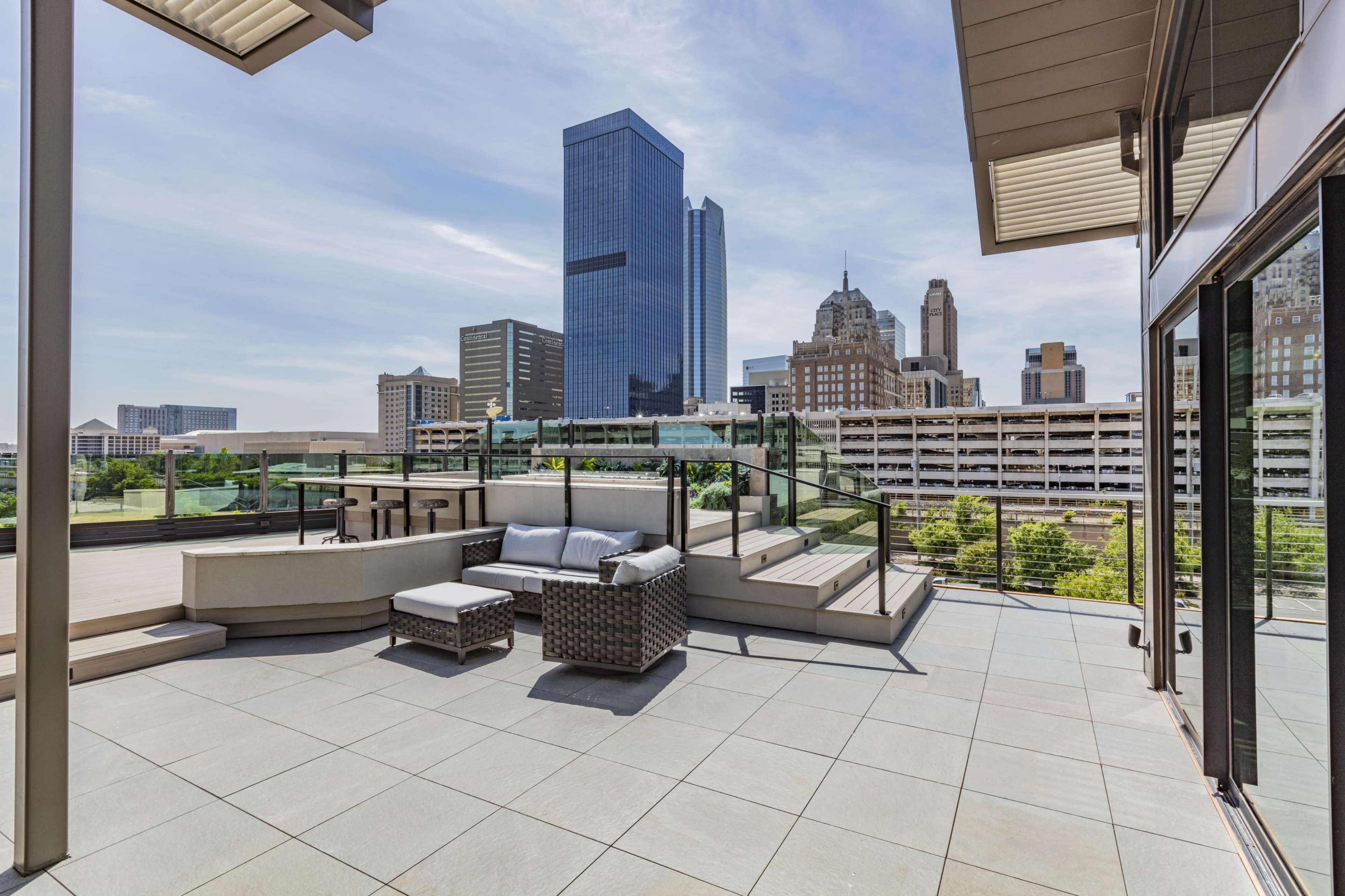 A terrace space features outdoor seating with a view of a city skyline and tall buildings.