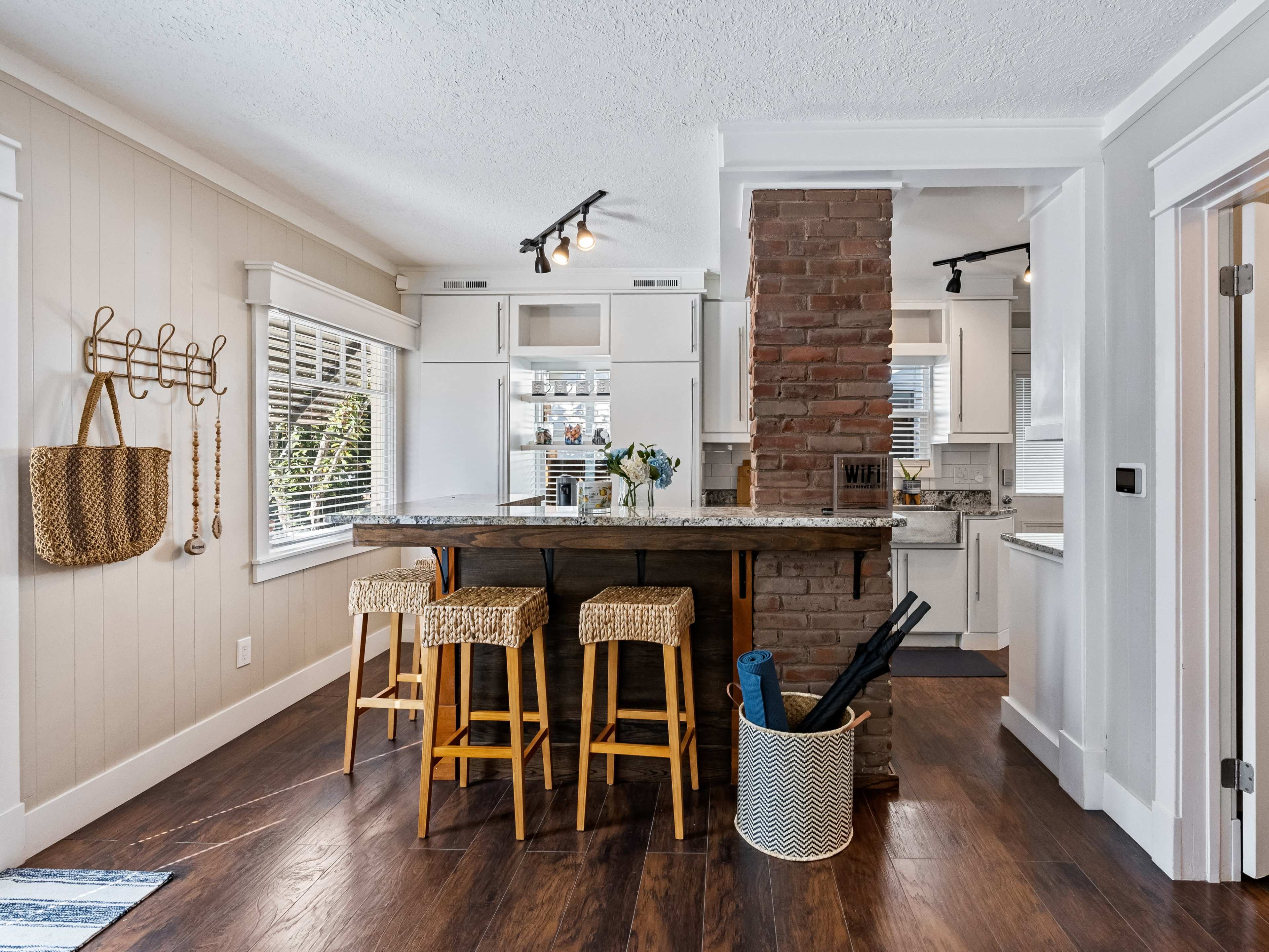 A kitchen featuring a stone column with a breakfast bar, three stools, and light-colored cabinetry.