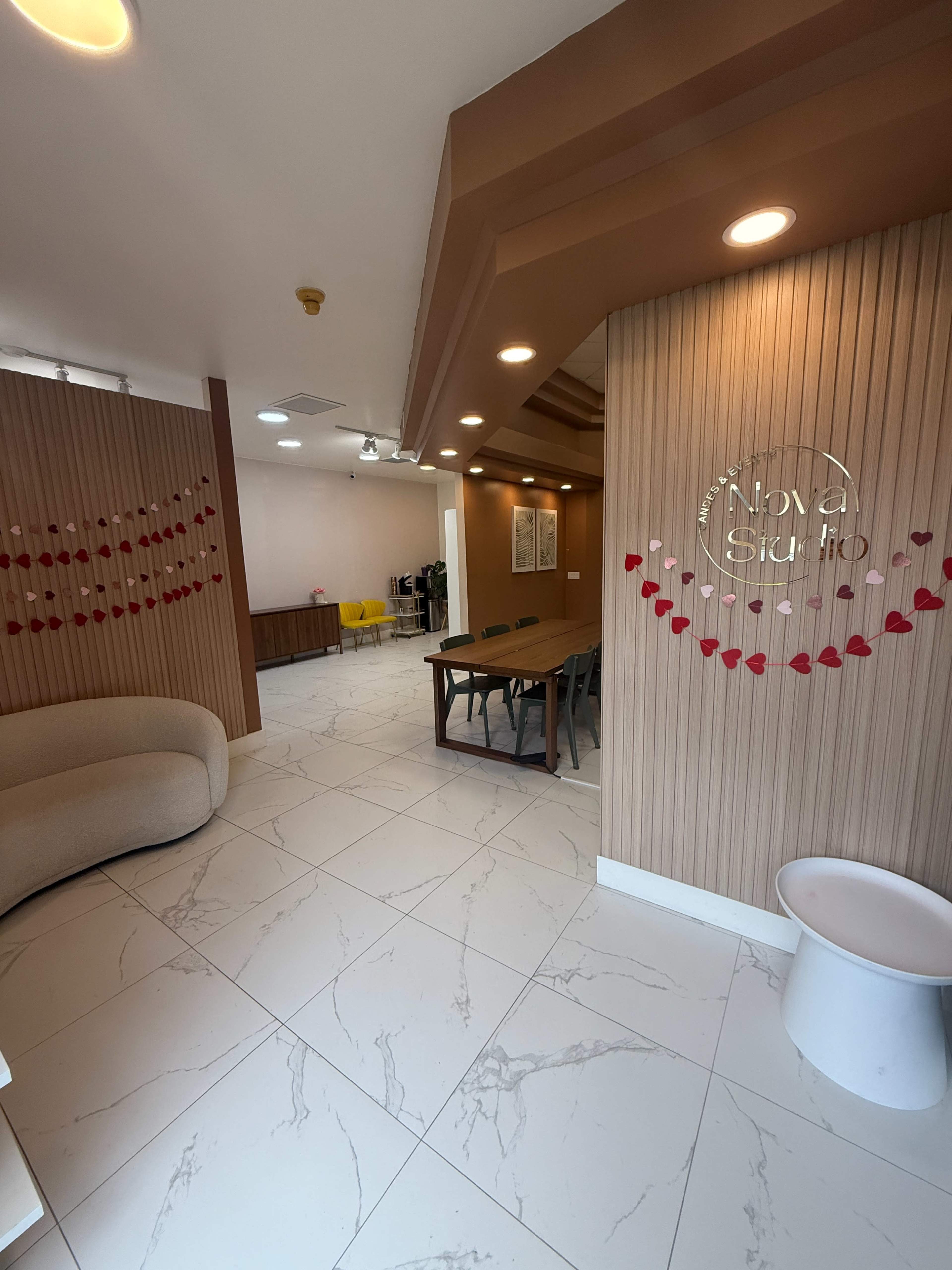 The image shows a modern interior space featuring a seating area, a dining table, and decorative heart-shaped elements on the walls.