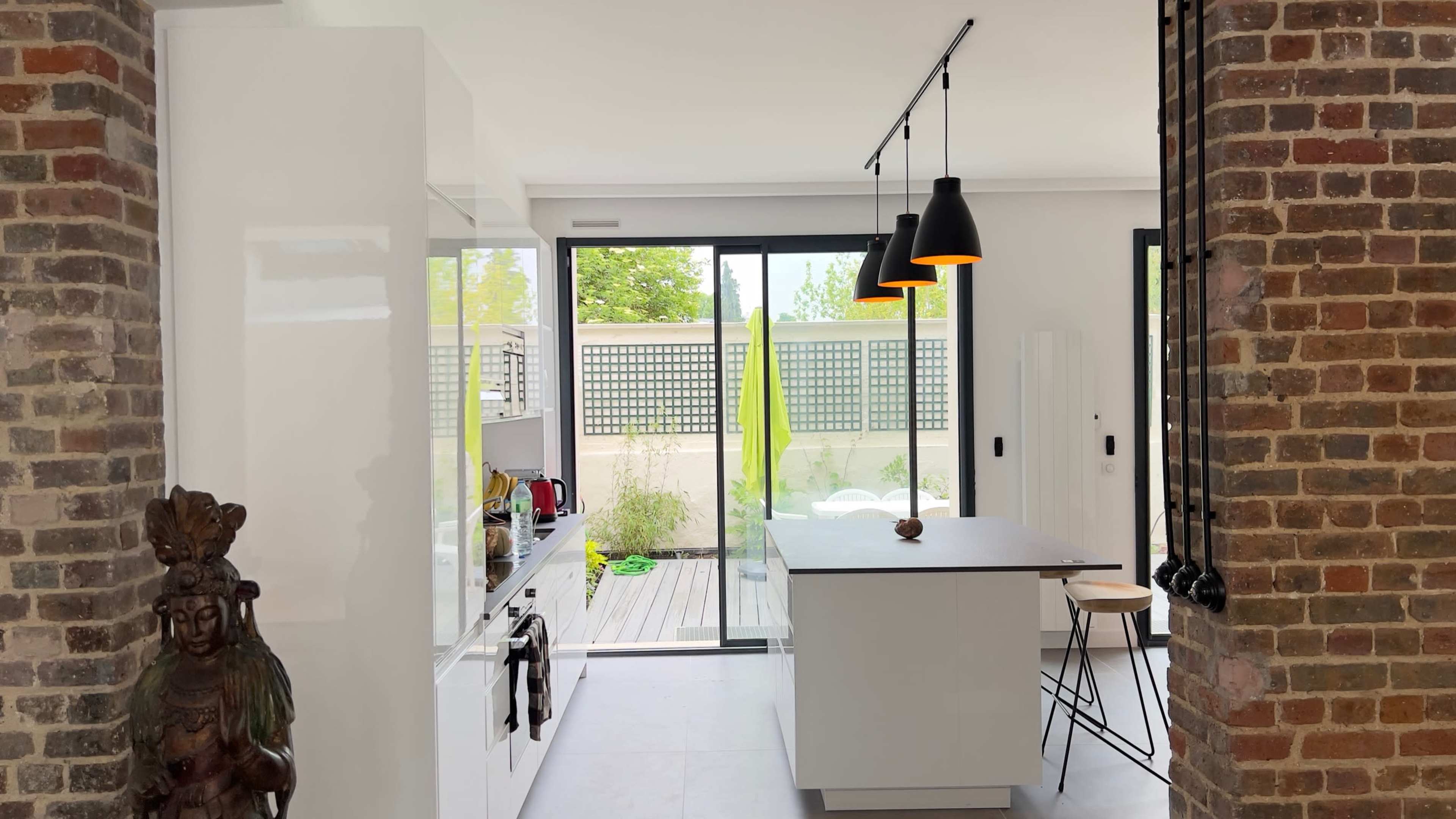 A modern kitchen with white cabinetry, an island with a black countertop, and large glass doors leading to an outdoor area.