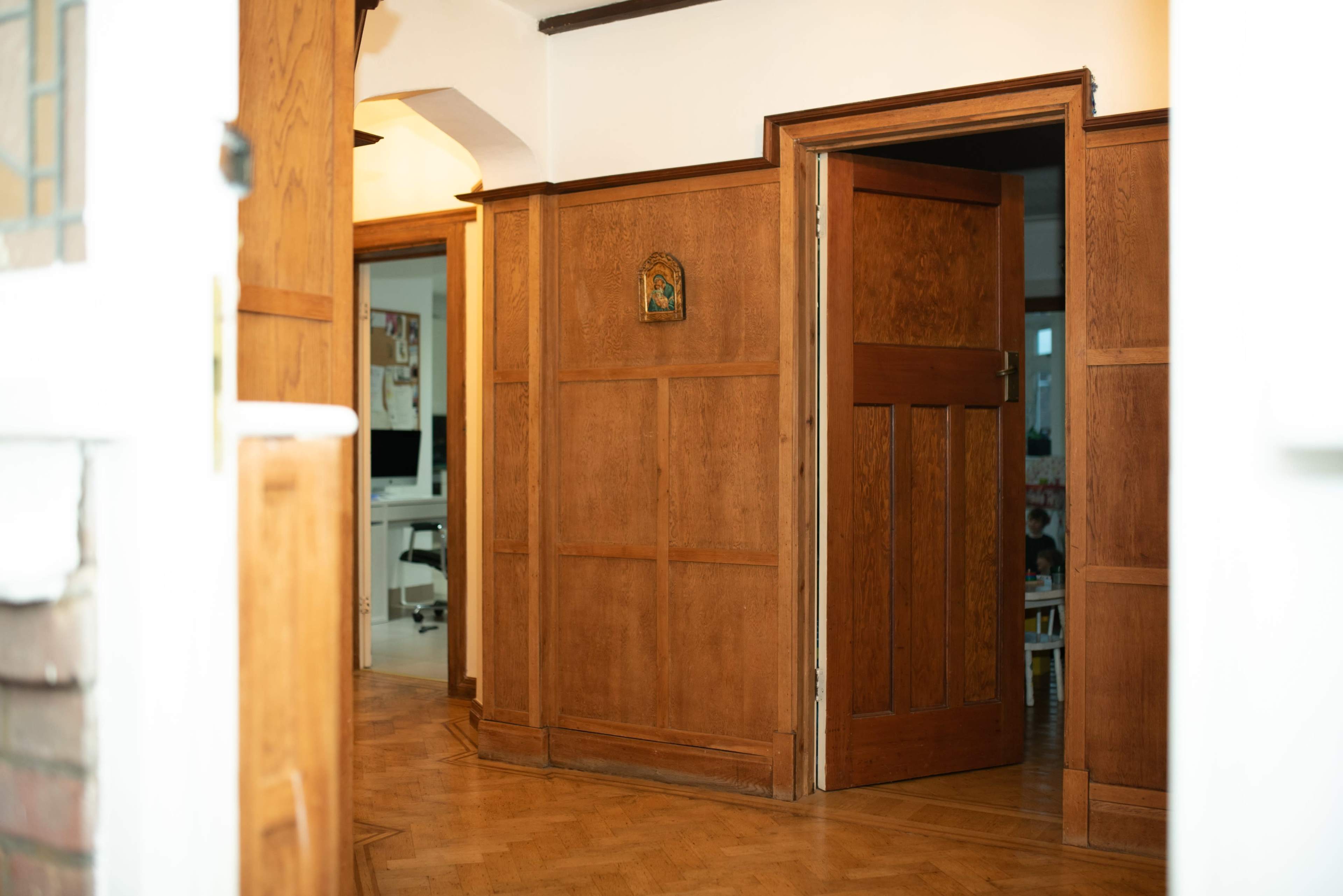 A wooden-paneled hallway with doorways leading to different rooms.
