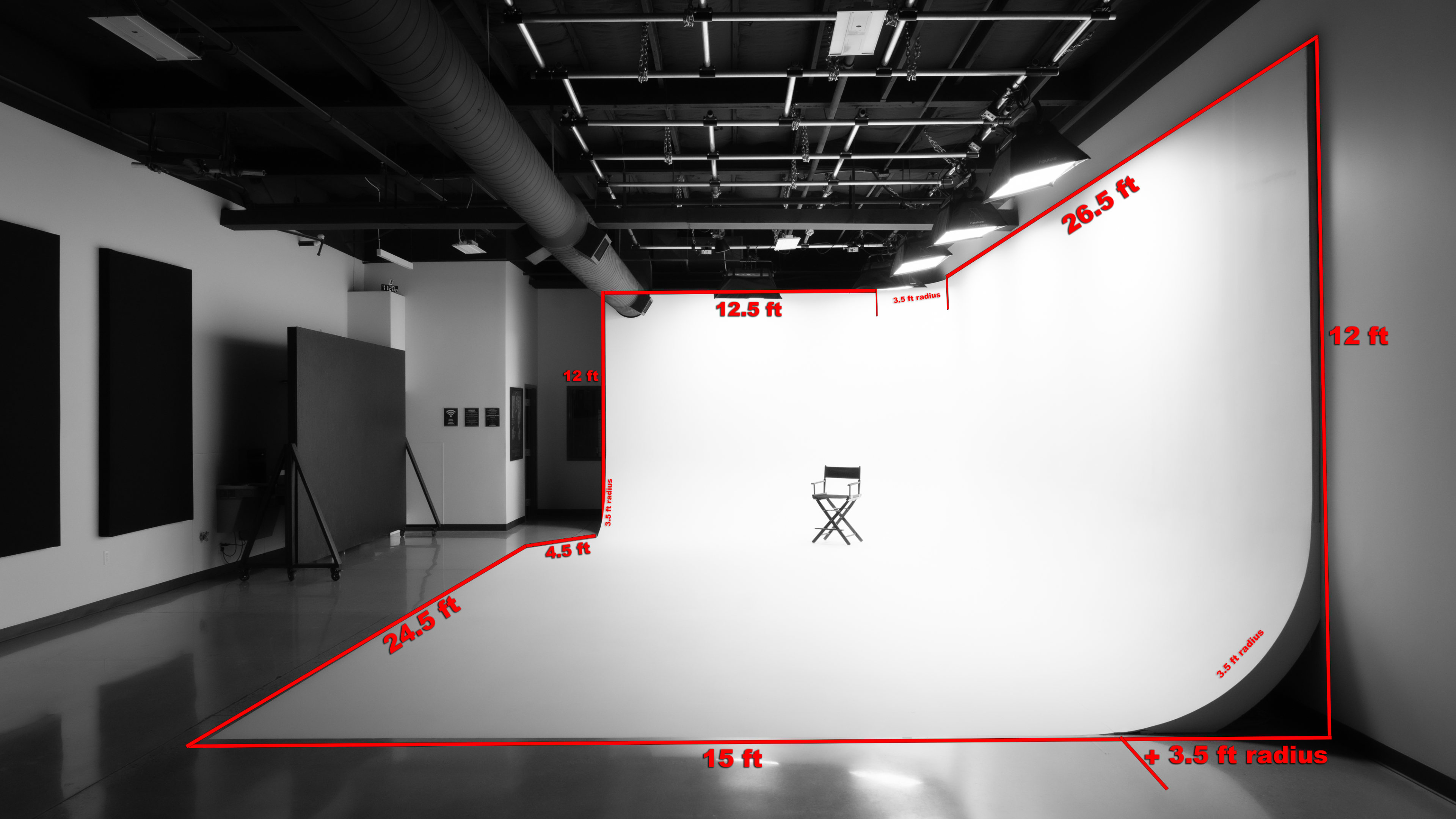 The image shows a photography studio with a large white backdrop and a single black chair positioned in front of it, along with various measurements indicated on the walls.