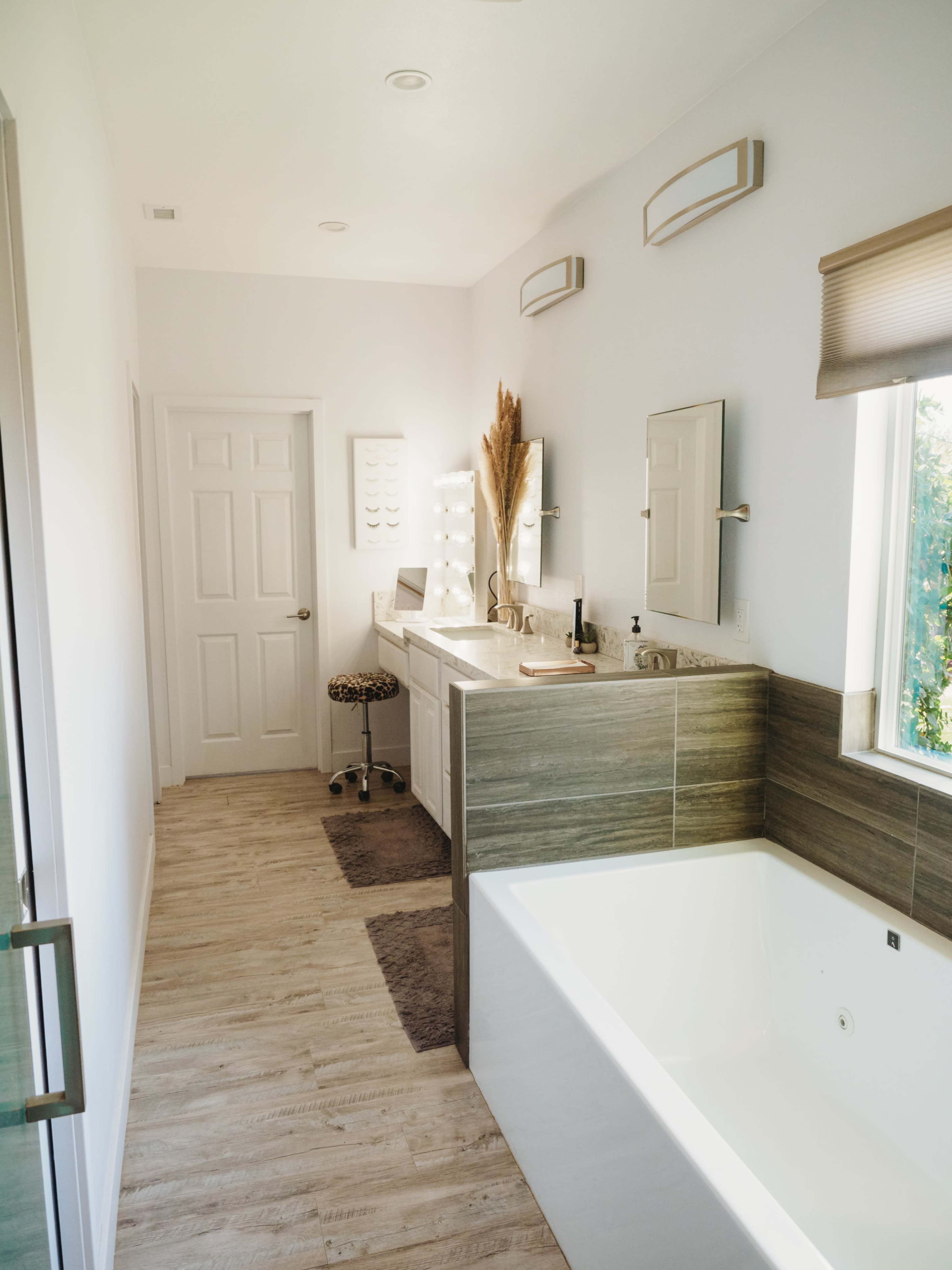 A modern bathroom with a double sink vanity, a bathtub, and large windows letting in natural light.