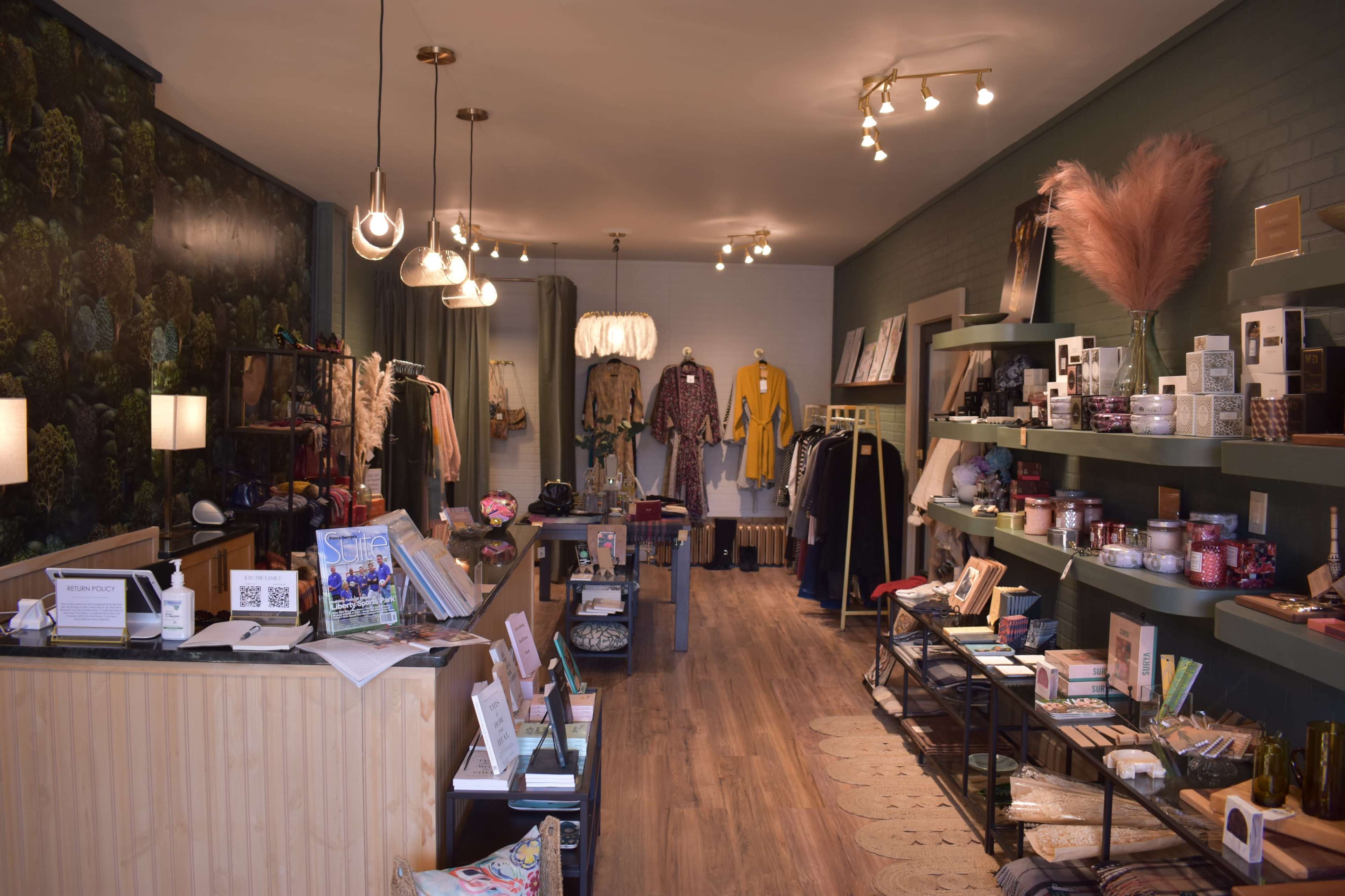 A retail shop interior with clothing racks, display shelves, and decorative lighting.