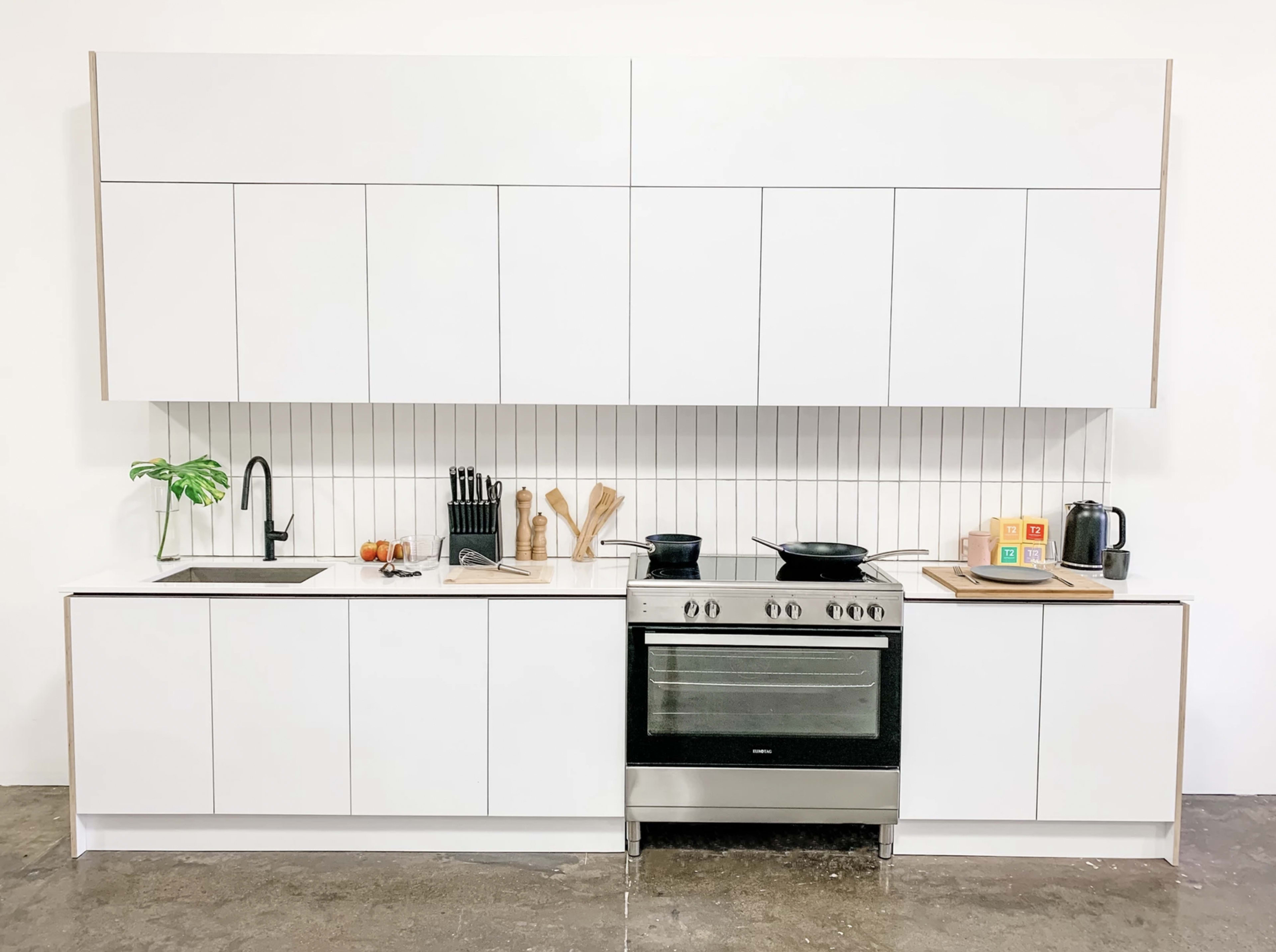 A modern kitchen features white cabinetry, a stainless steel stove, and essential cooking tools displayed on a countertop.