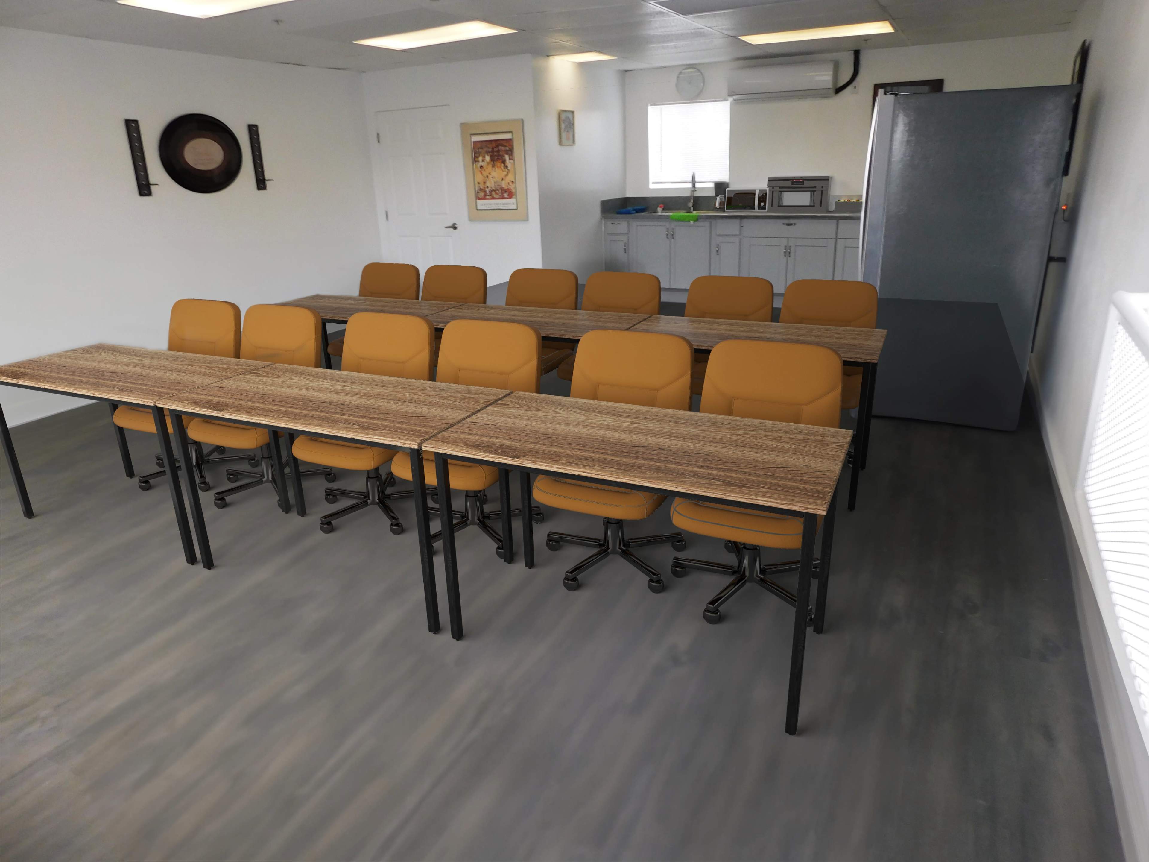 The image shows a meeting room with two rows of tables and chairs facing a wall, featuring a kitchenette in the background.