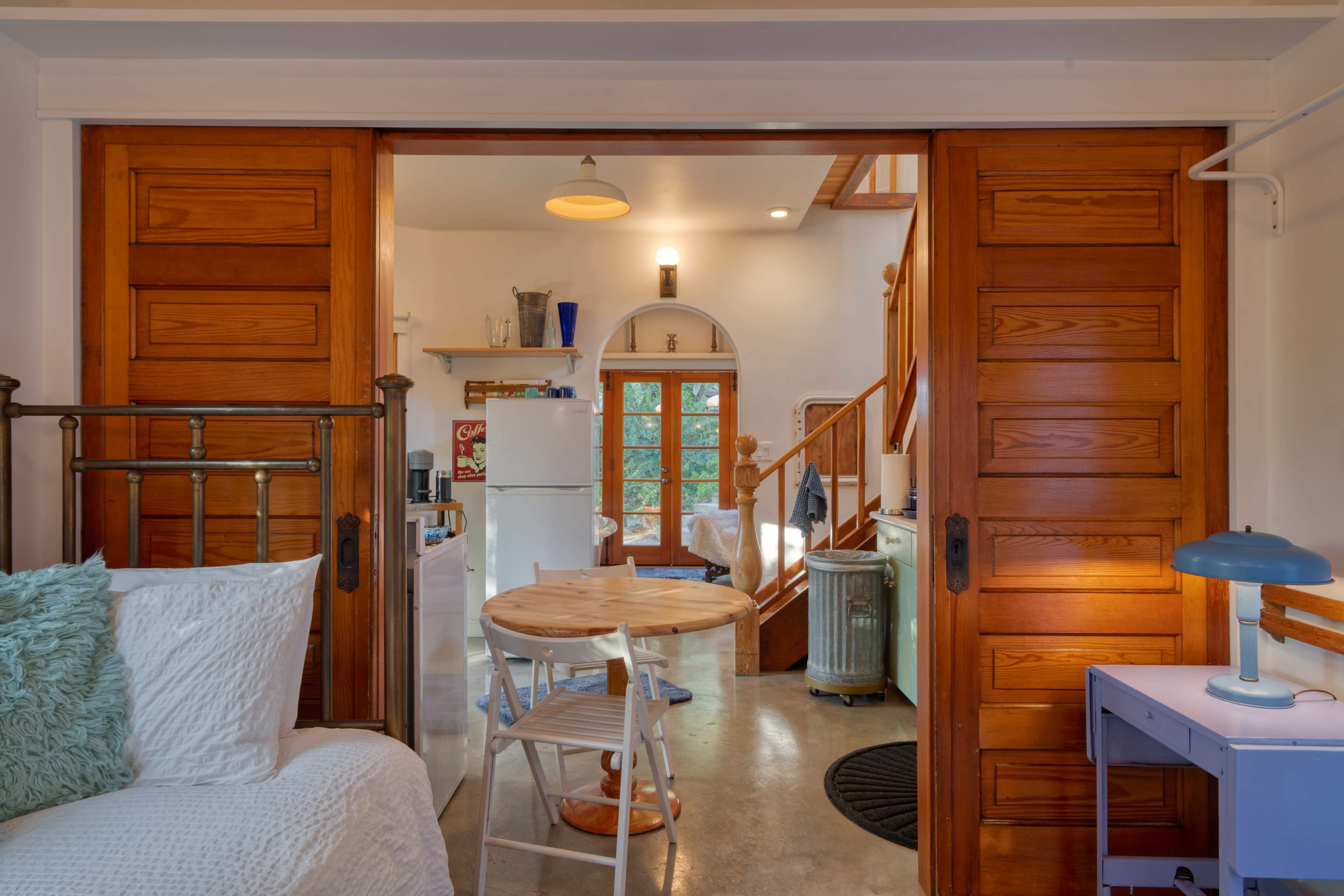 A view shows a cozy interior space with wooden doors leading to a kitchen area and a staircase.