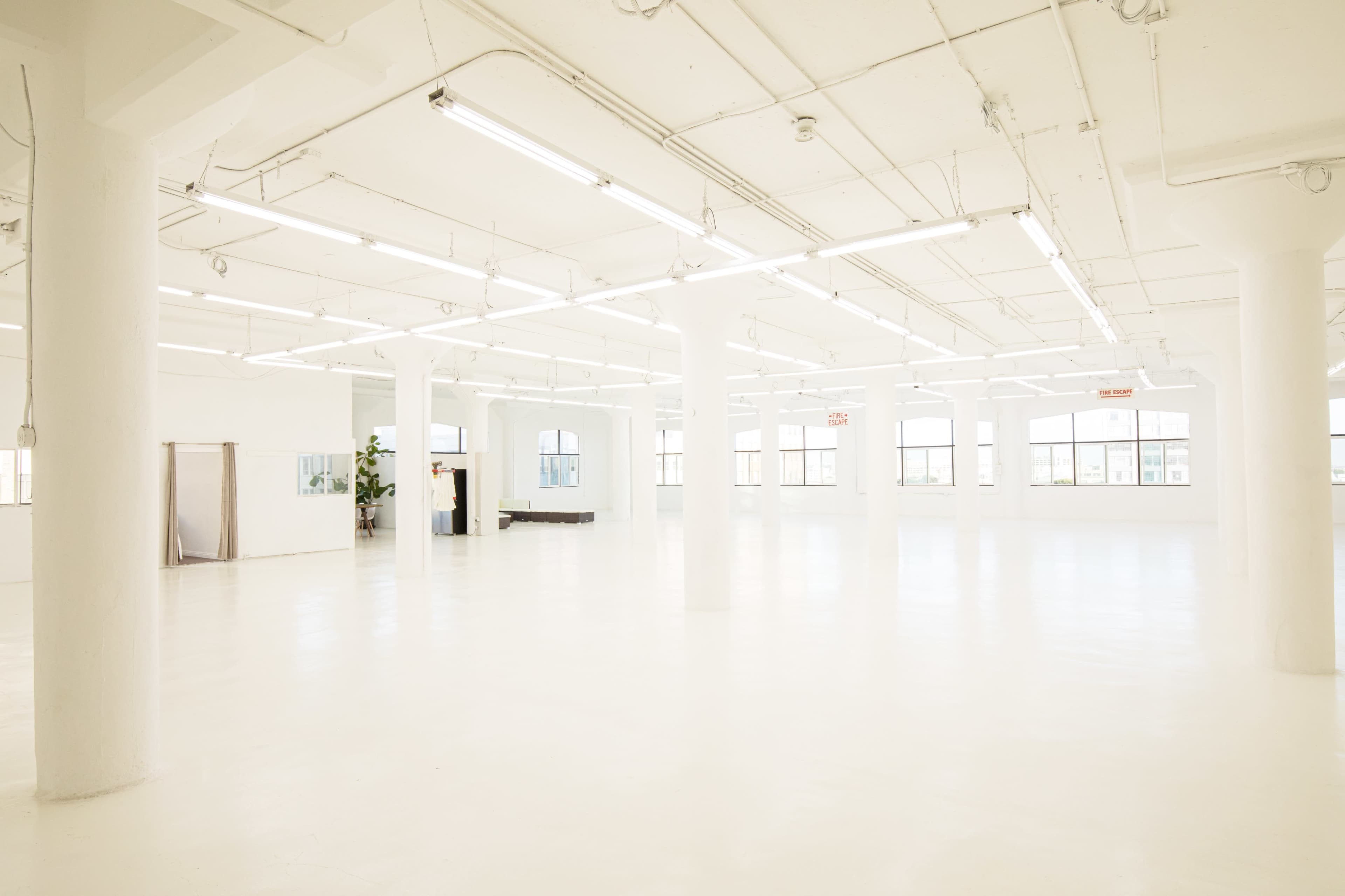 A spacious, well-lit interior with white walls, a polished floor, and several columns.