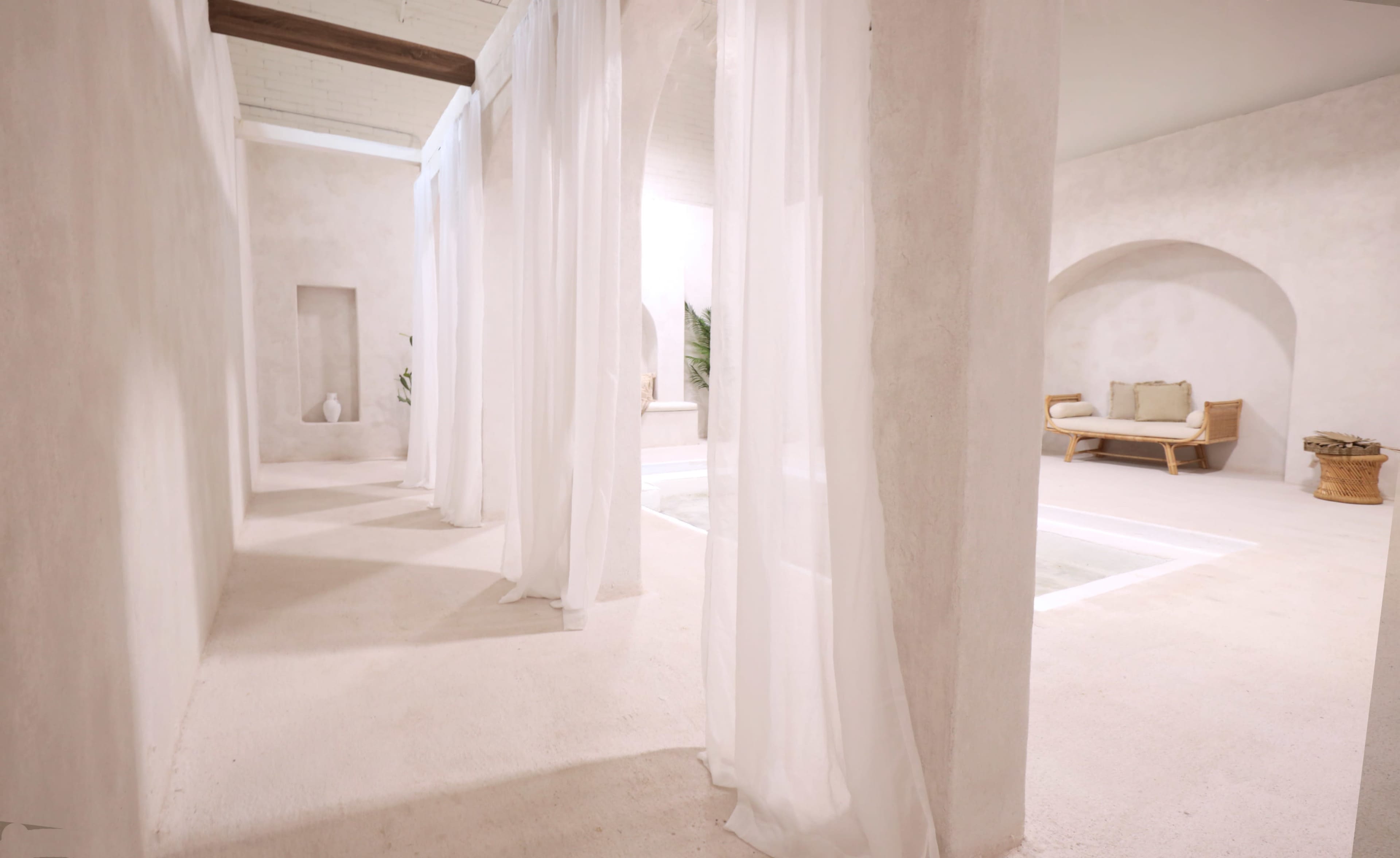 A minimalist spa interior with sheer white curtains, light-colored walls, and a peaceful seating area.