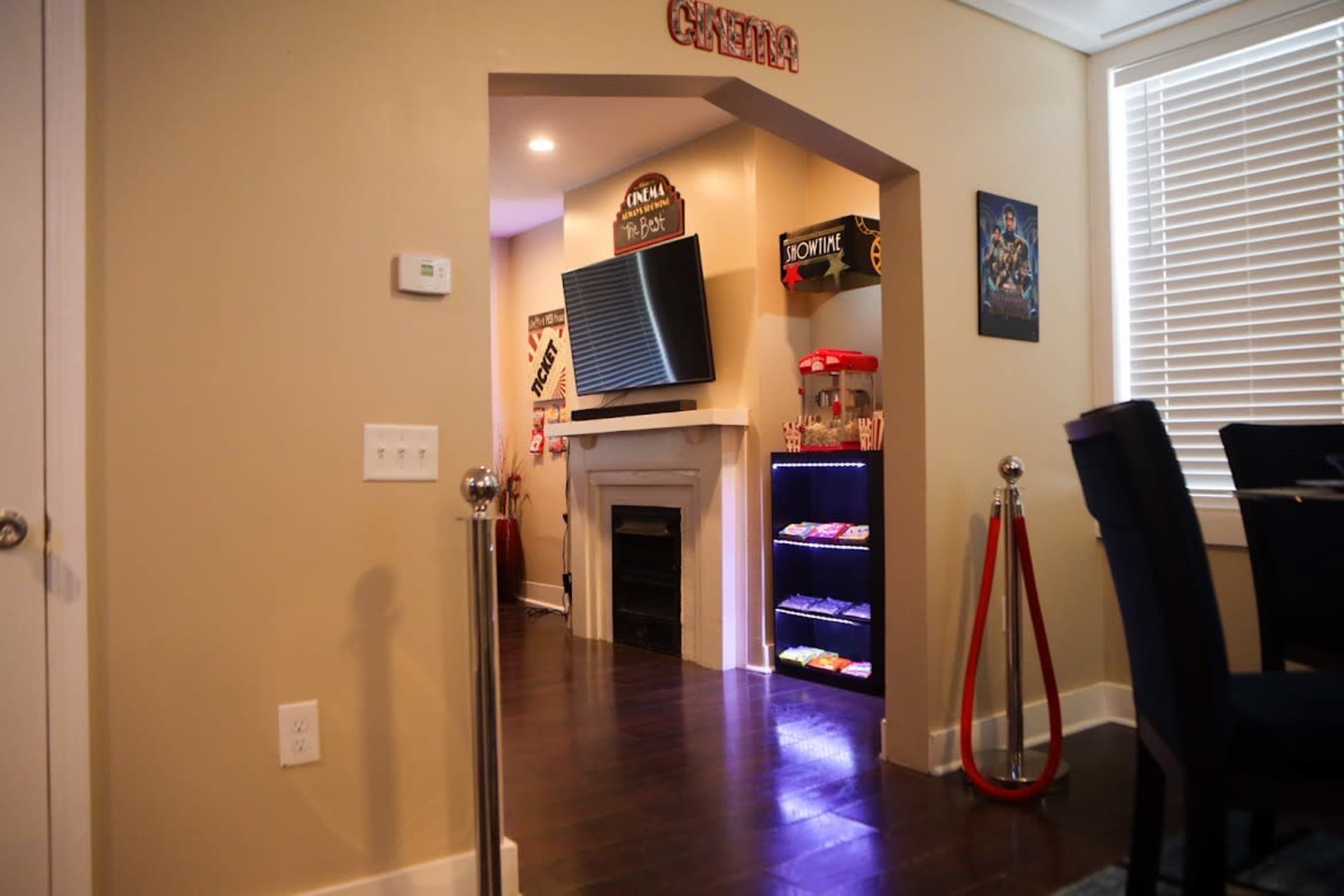 A home theater area with a television mounted above a fireplace and a snack station with a red carpet leading to it.