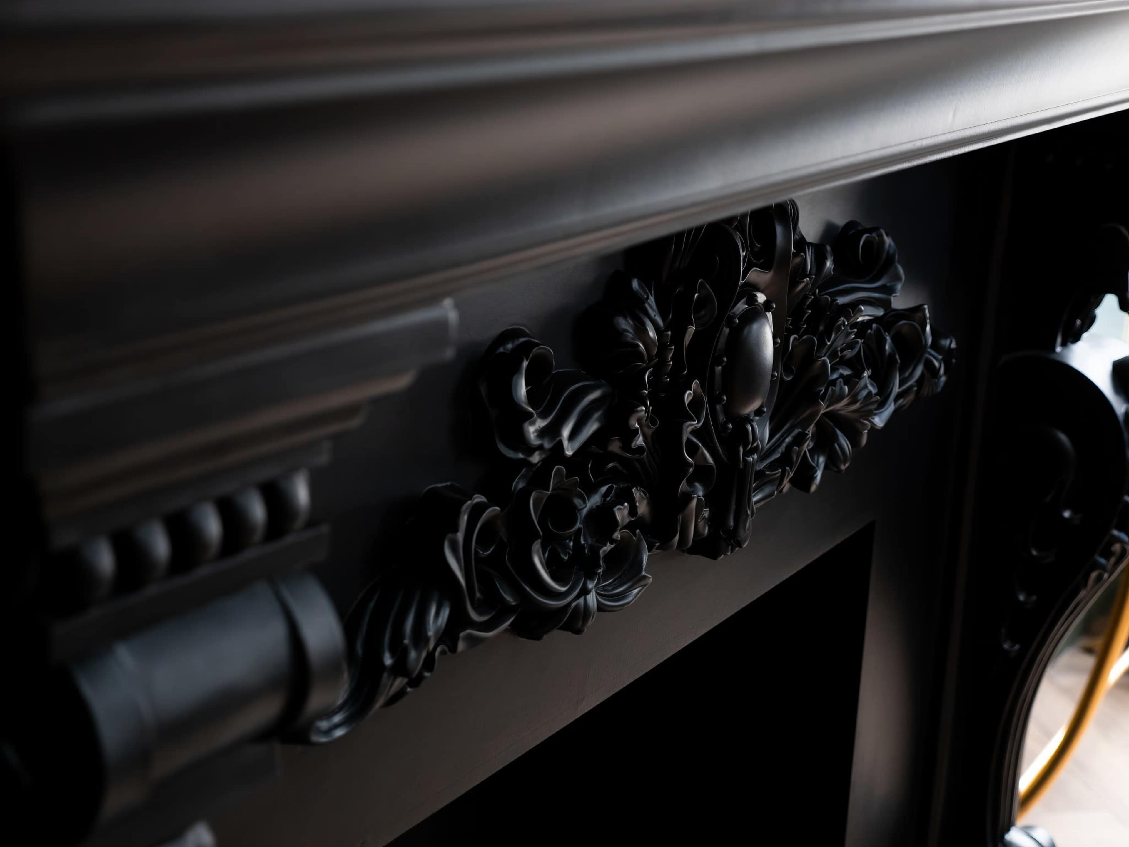A detailed black mantelpiece adorned with ornate floral carvings.