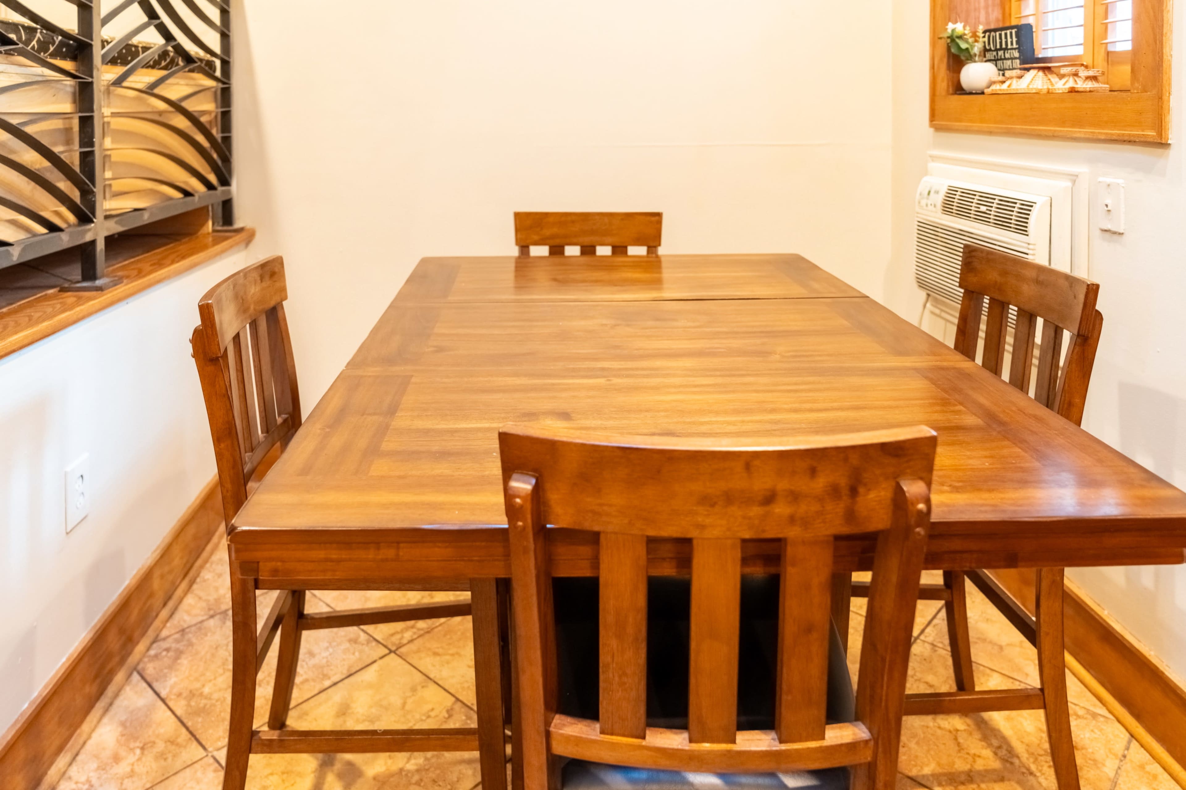 A wooden dining table with four matching chairs is positioned in a well-lit room.