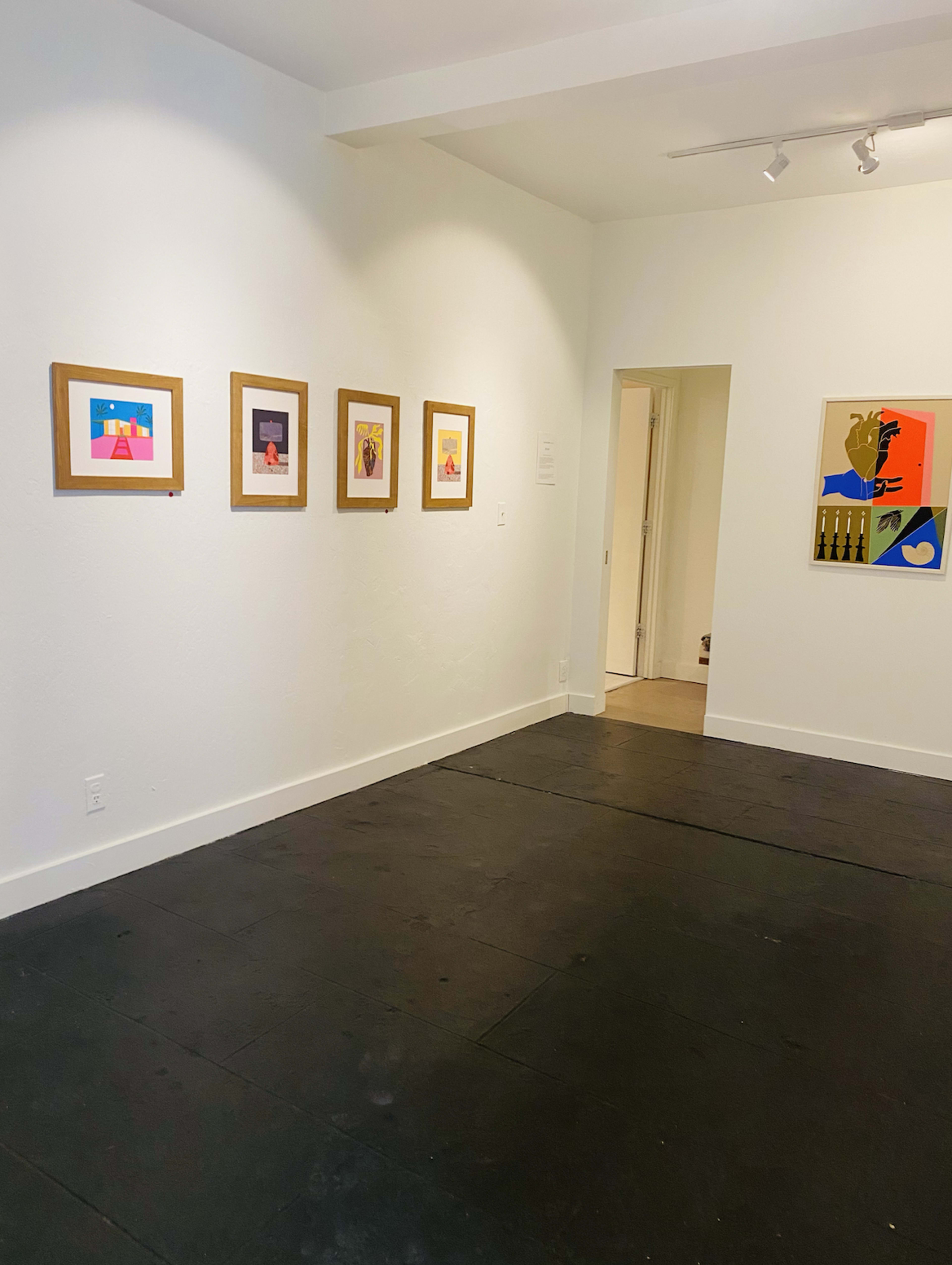 The image shows an art gallery with white walls displaying five framed artworks aligned on one side and an open doorway leading to another room.