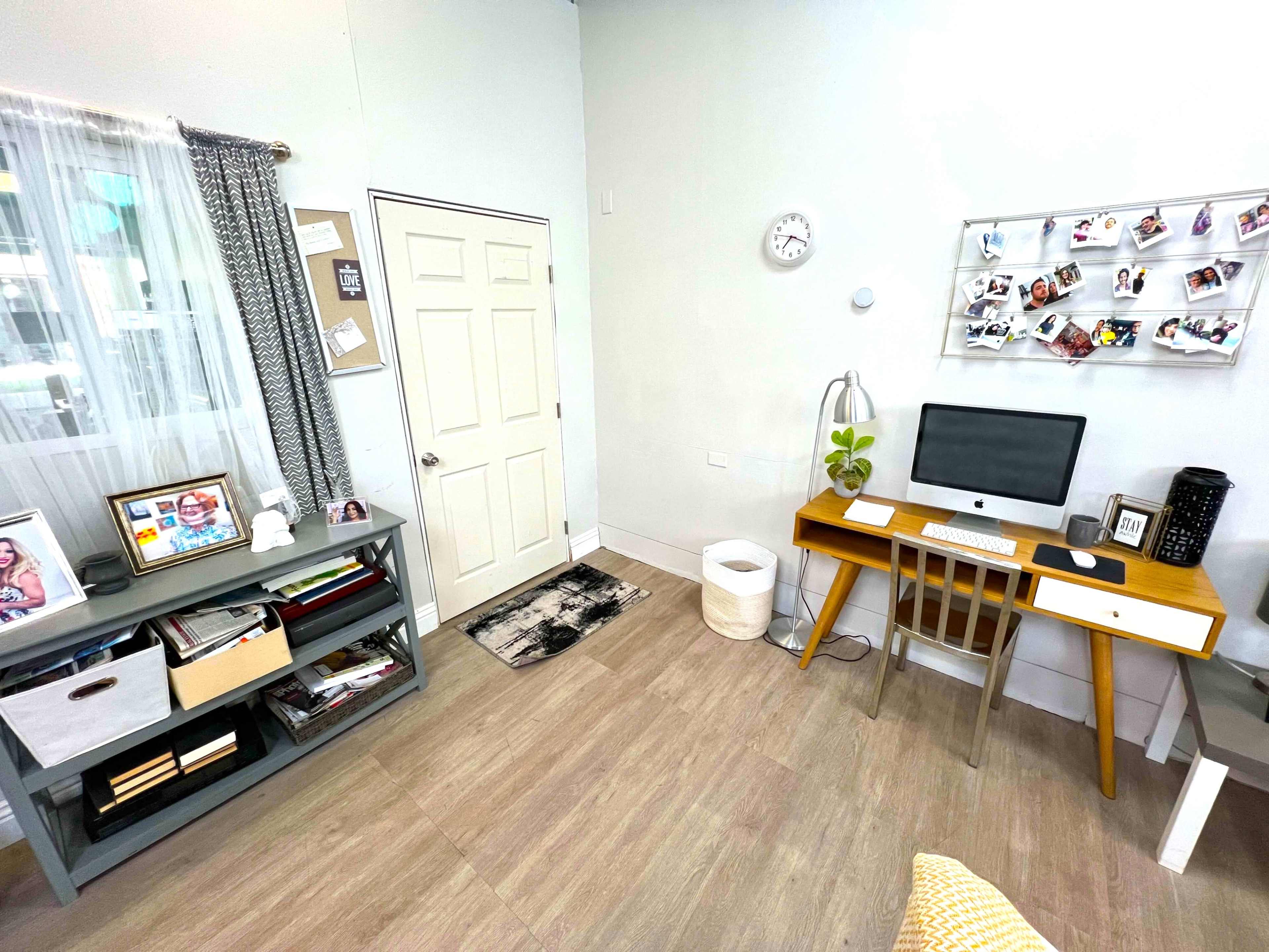 The image shows a modern home office with a desk, computer, and decorative elements, along with a door and a bookshelf against the wall.