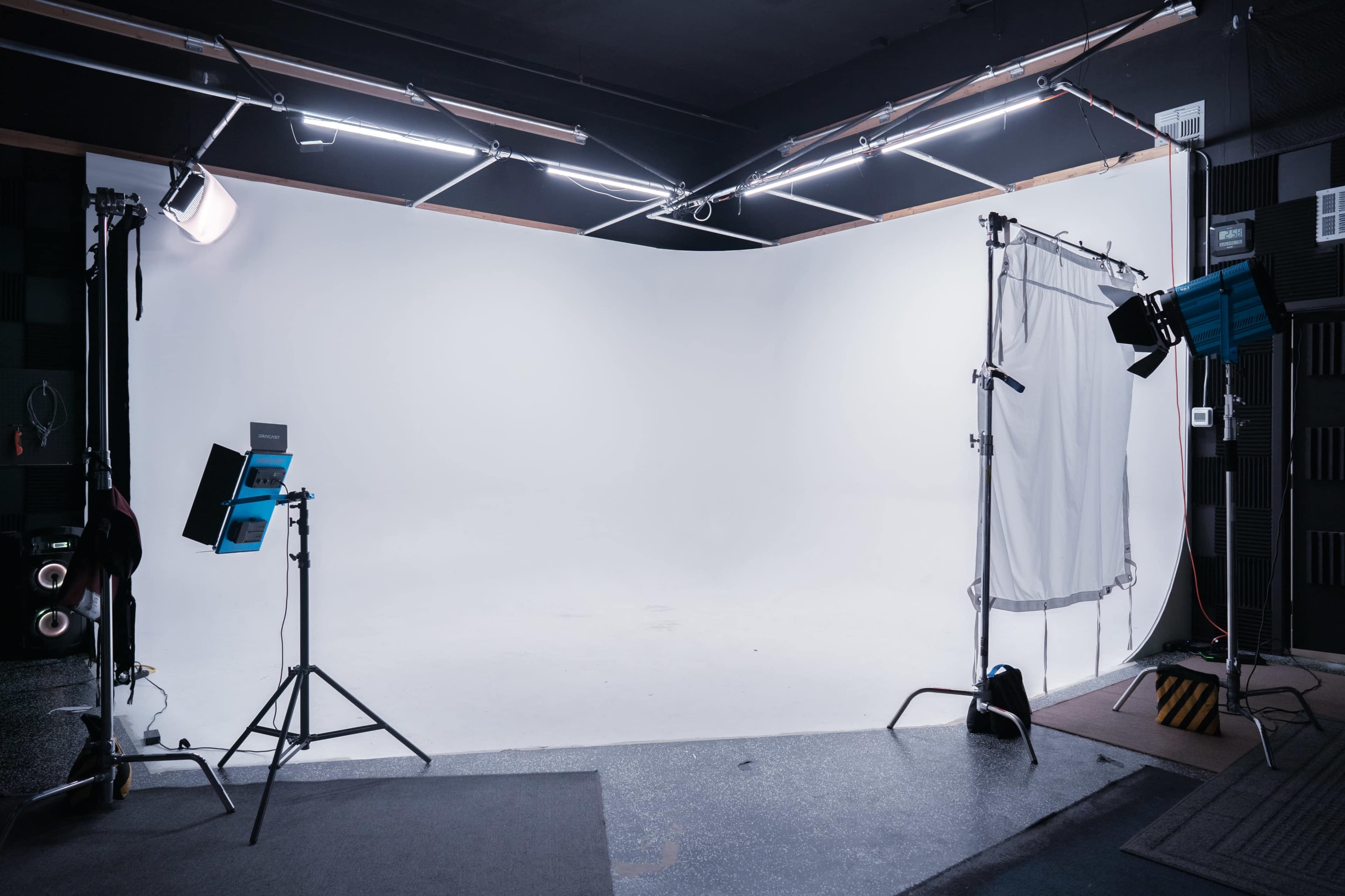 A photography studio with a large white backdrop and various lighting equipment set up on tripods.