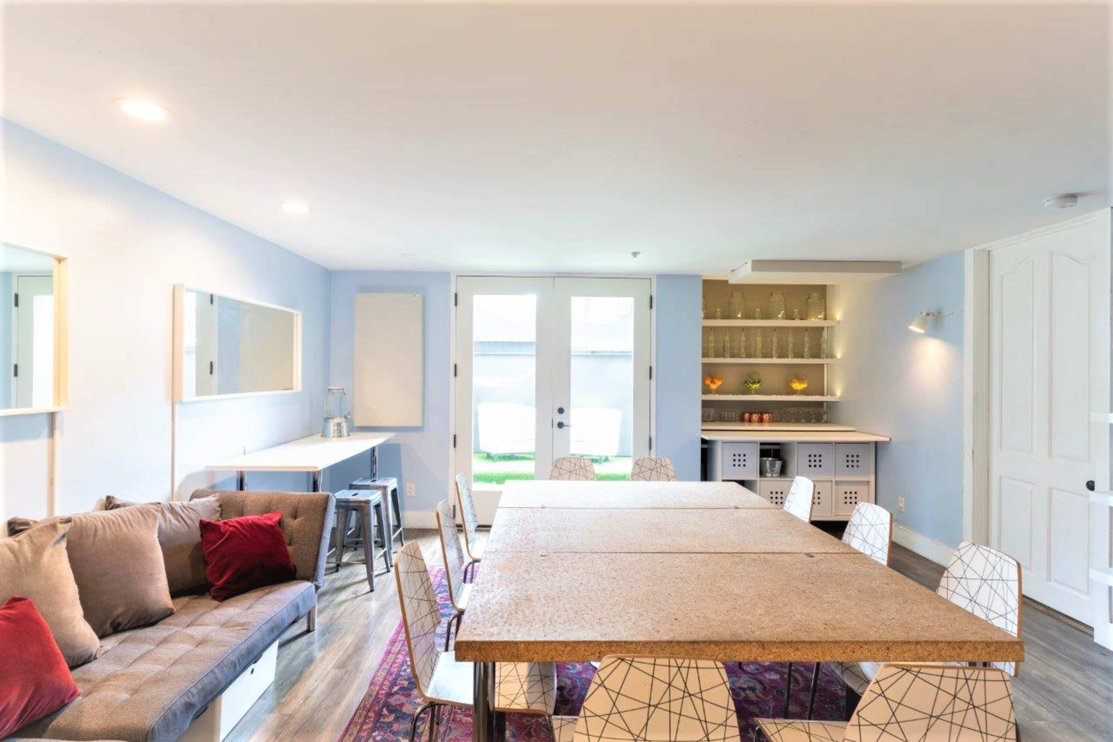 A spacious room features a large table surrounded by chairs, a couch in the corner, and built-in shelves displaying decorative items.