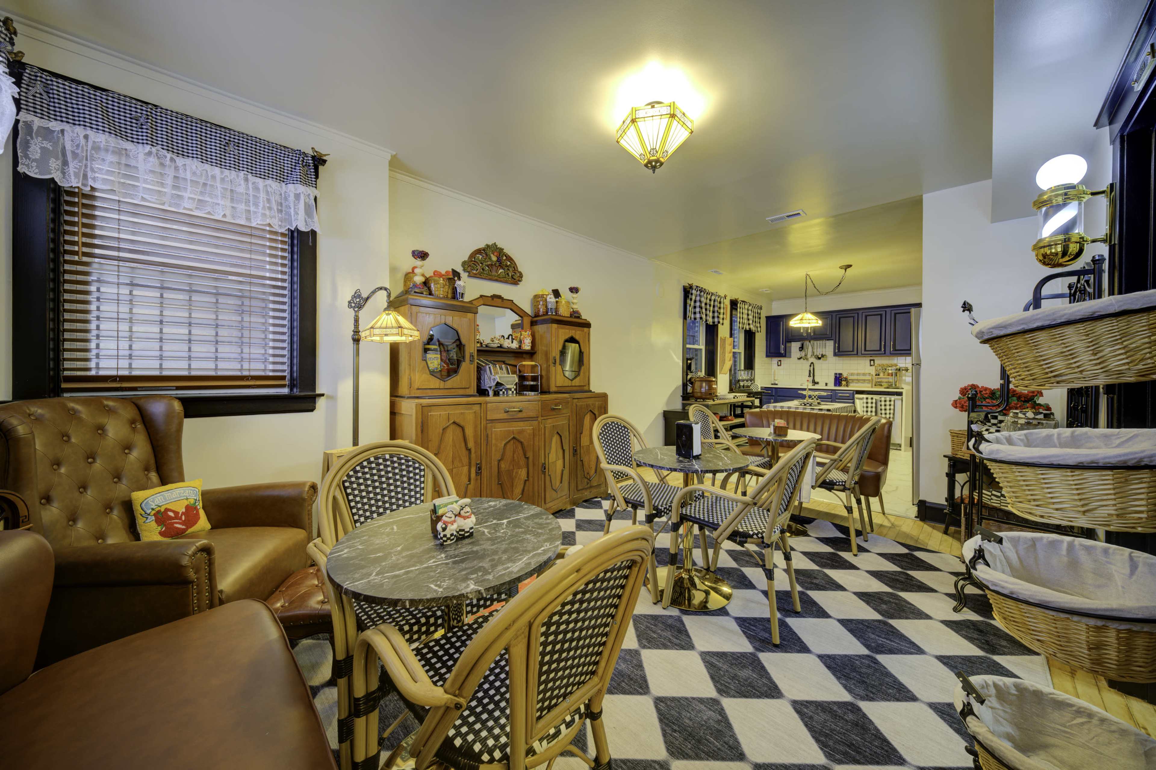 The image shows a cozy café with wooden furniture, a marble-topped table, wicker chairs, and a warm ambiance created by overhead lighting.