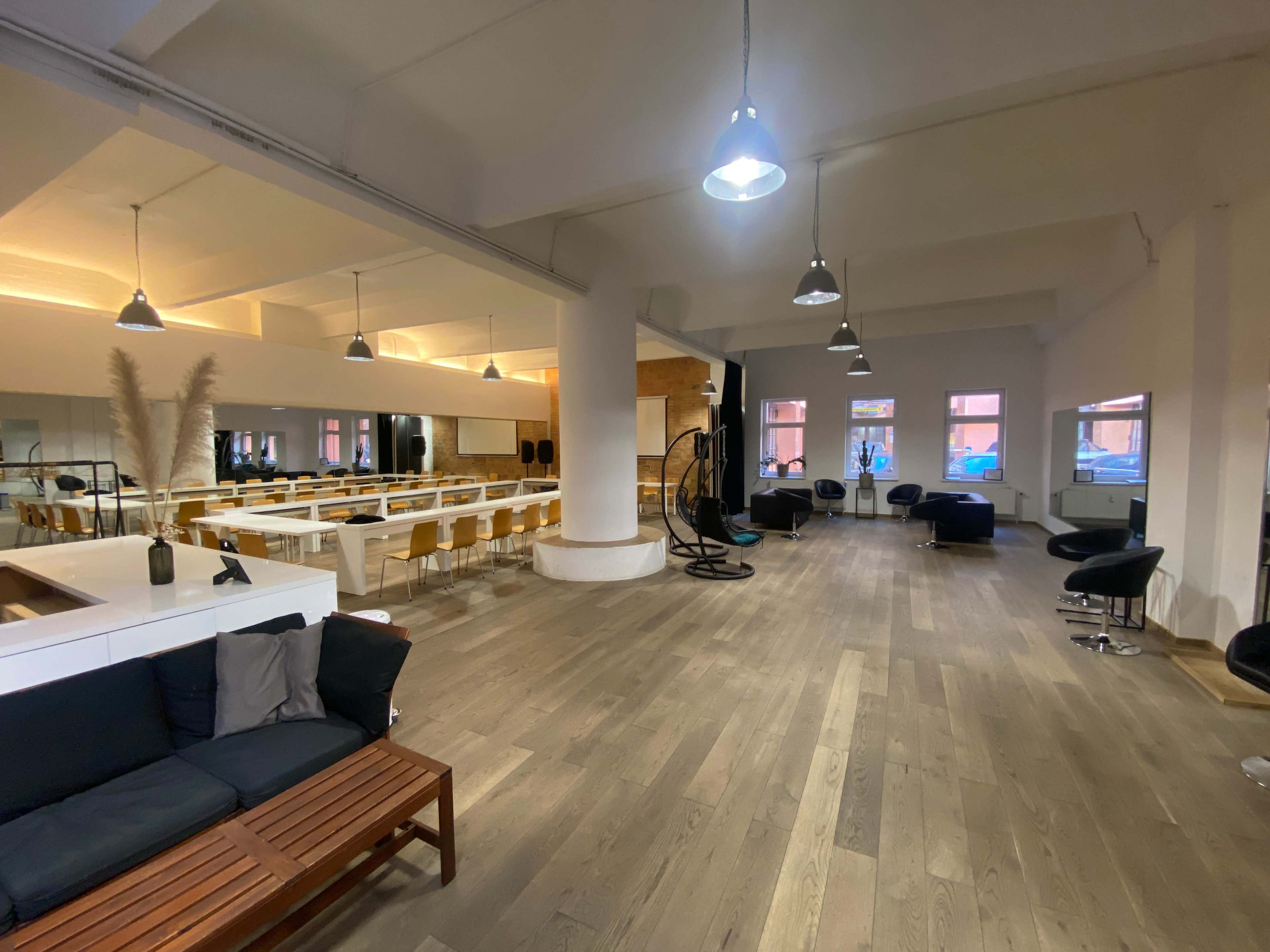 The image shows a spacious interior with a mix of seating areas, including a lounge section and several dining tables under modern lighting.