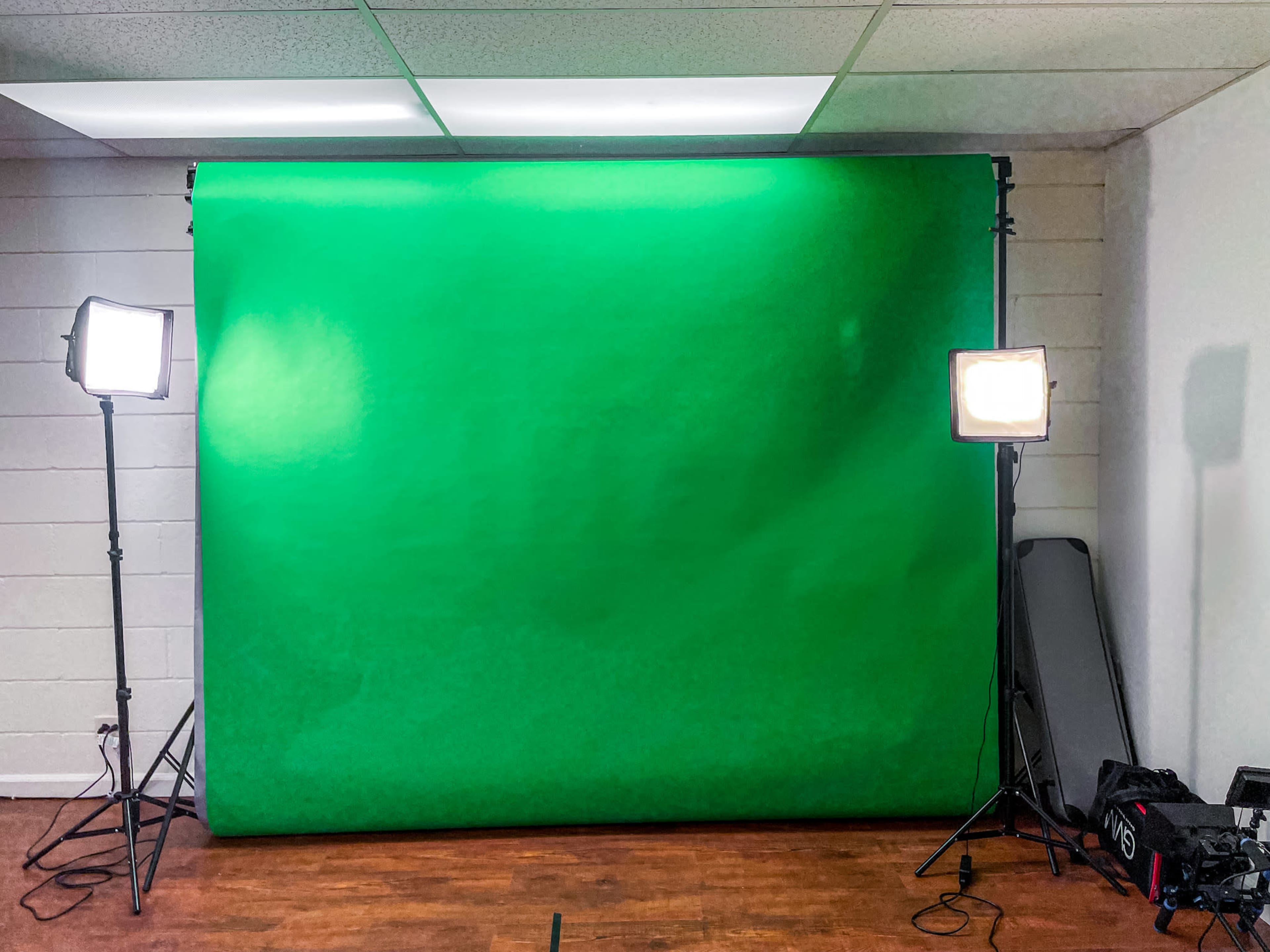 A green screen setup in a well-lit room with two studio lights positioned on either side.
