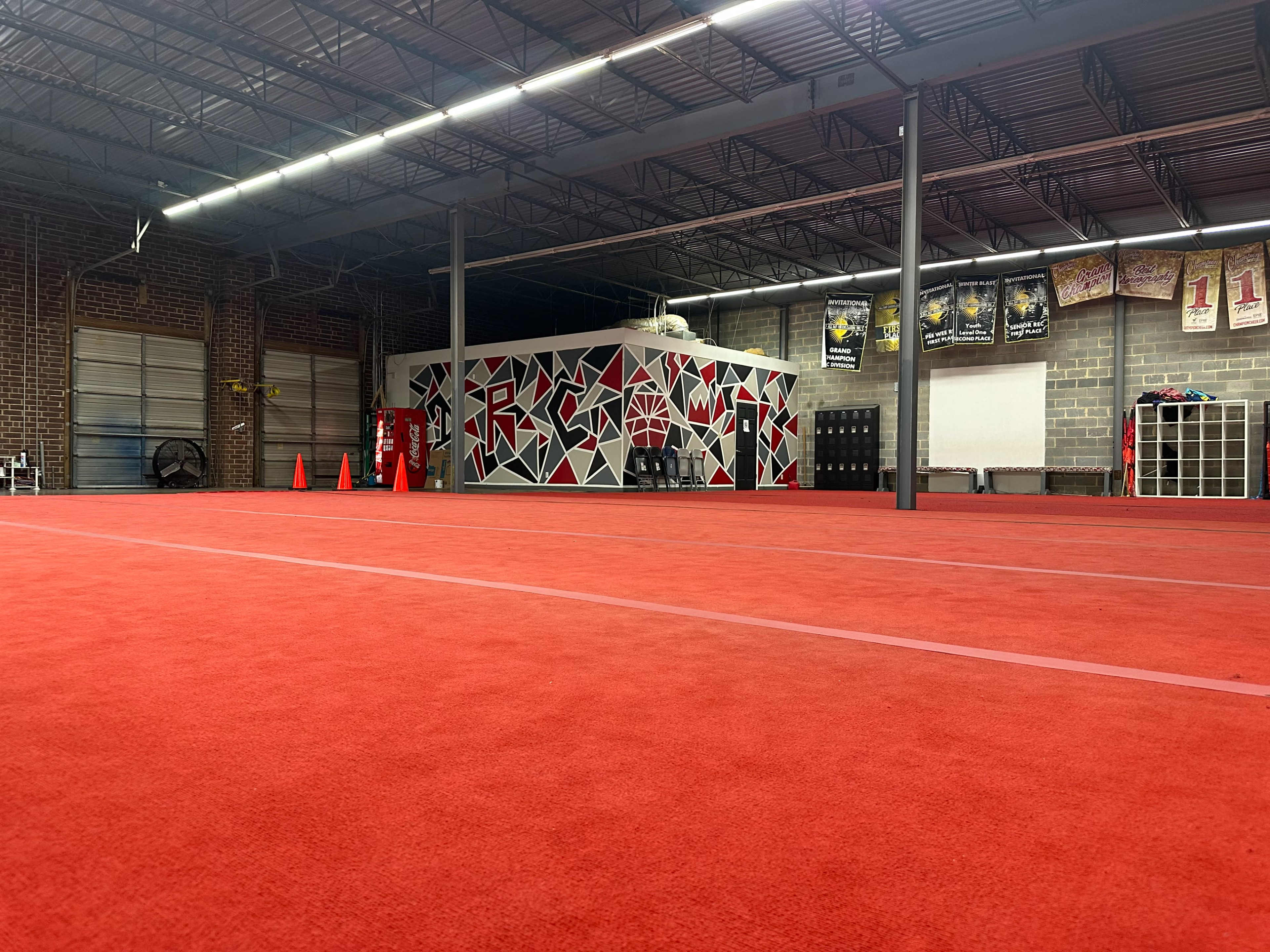 The image shows an indoor training facility with a red carpeted floor and a brightly painted wall featuring geometric shapes.