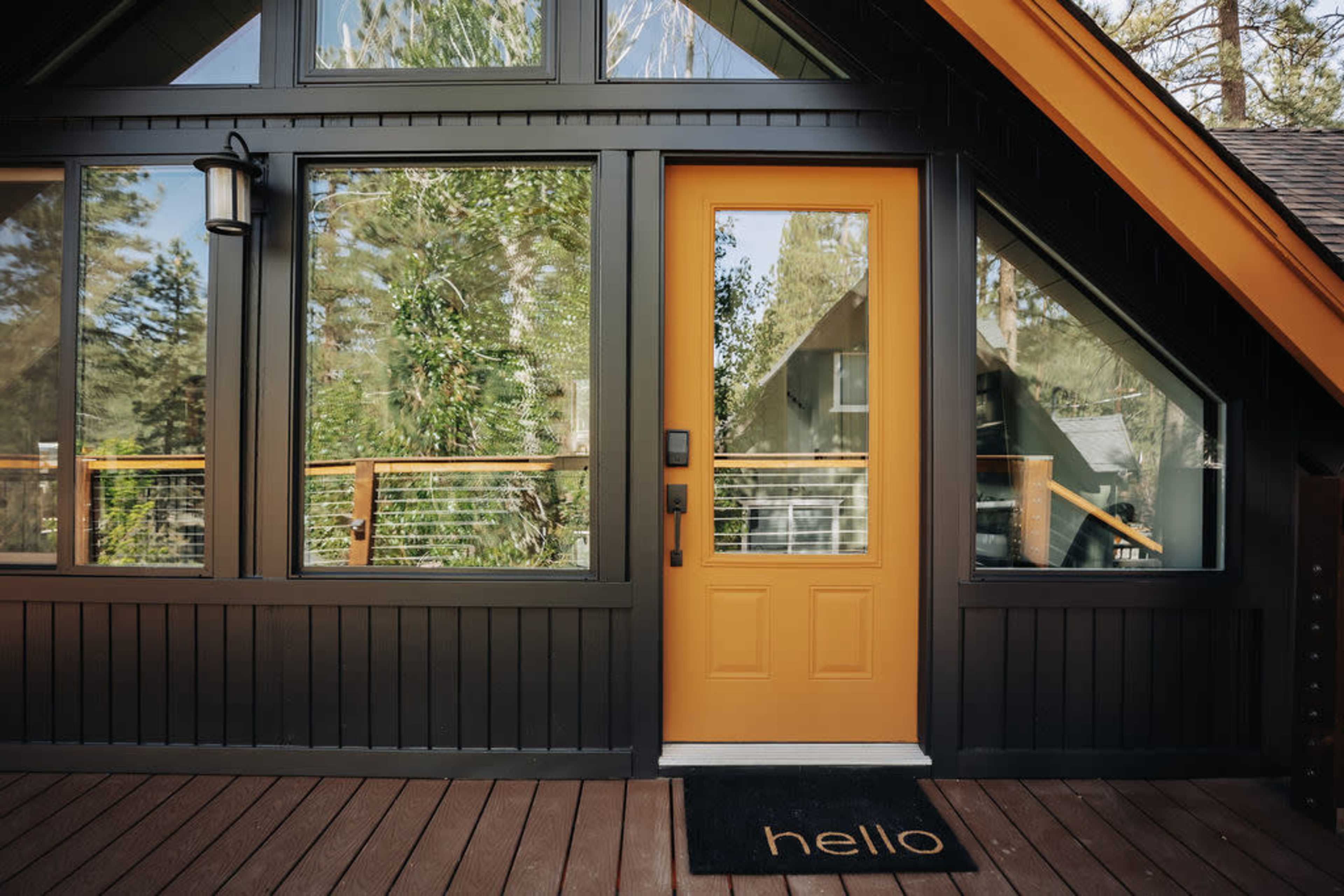A modern house entrance with a bright yellow door and a welcome mat that reads "hello."