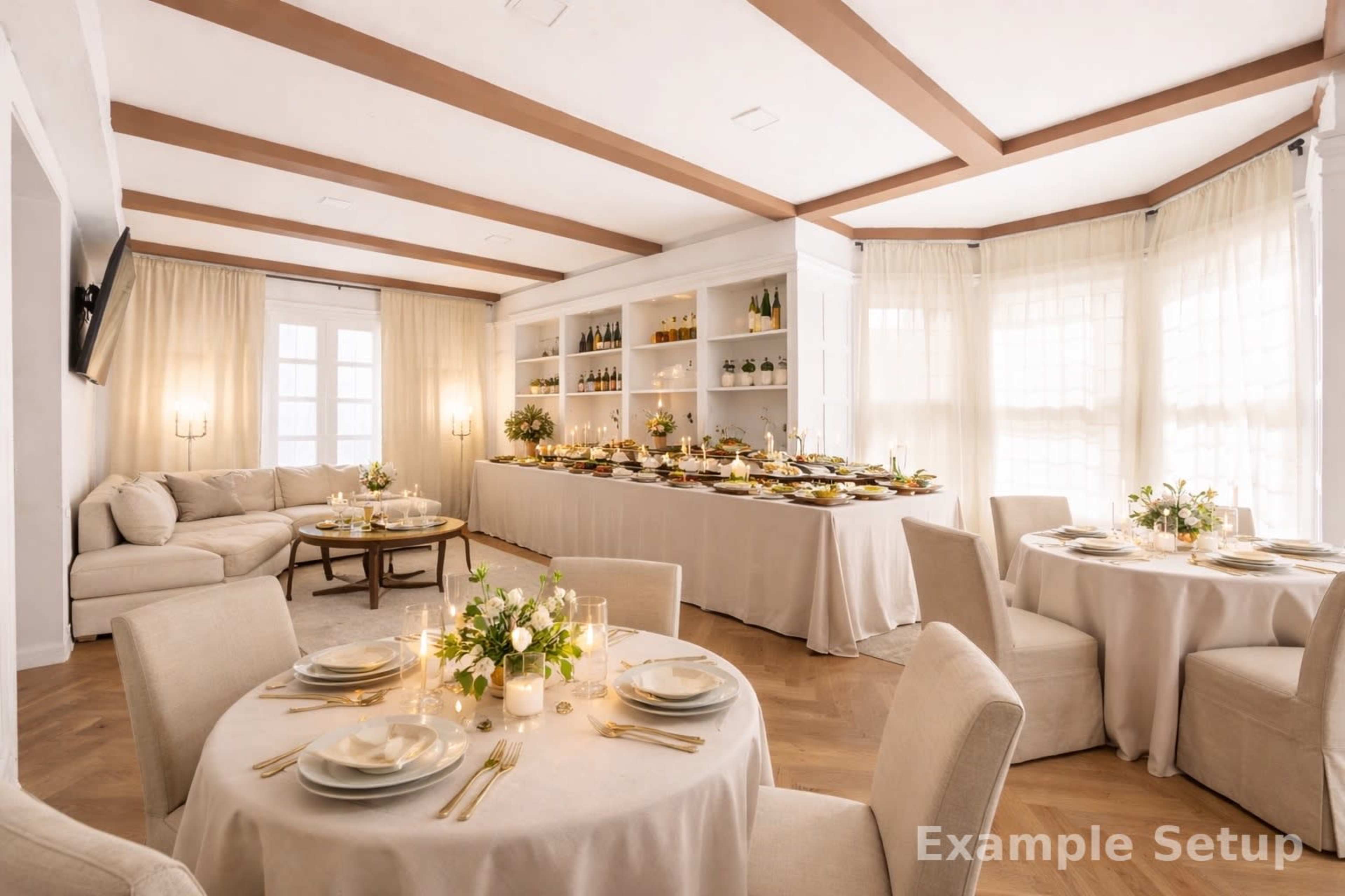 The image shows a stylish dining room set with elegantly arranged round tables, soft furnishings, and a long buffet table filled with food and drinks against a backdrop of large windows and light curtains.