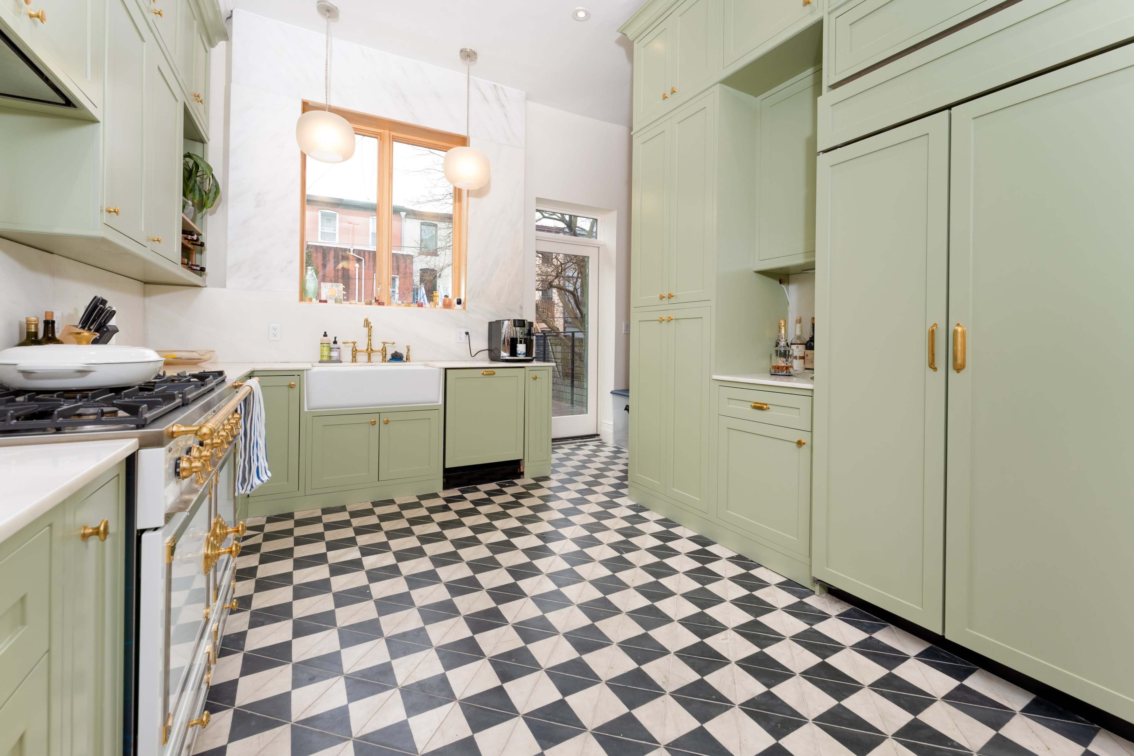 The kitchen features light green cabinetry, a farmhouse sink, and a black and white checkered floor.