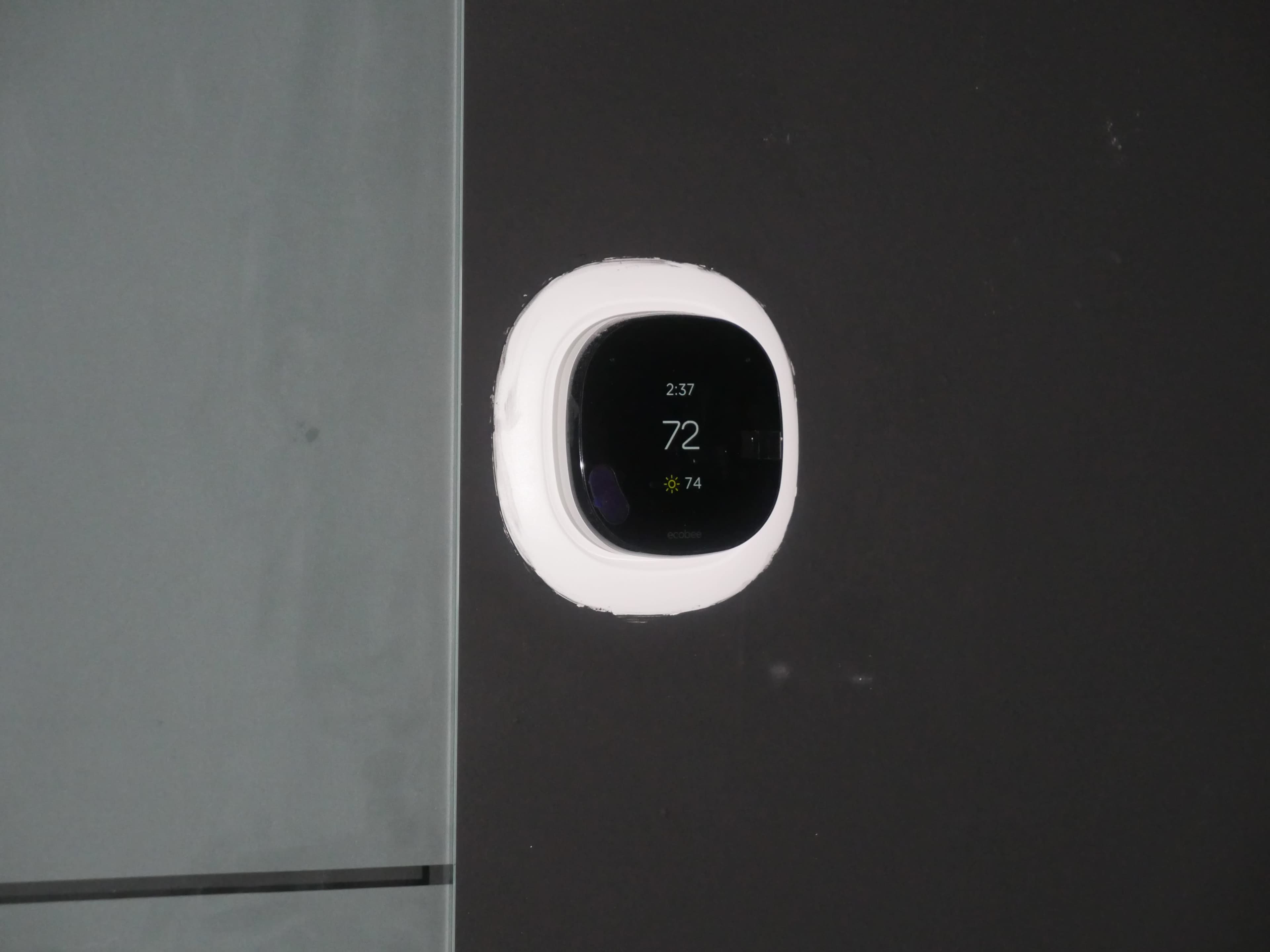 A digital thermostat displaying a temperature of 72°F is mounted on a dark wall.