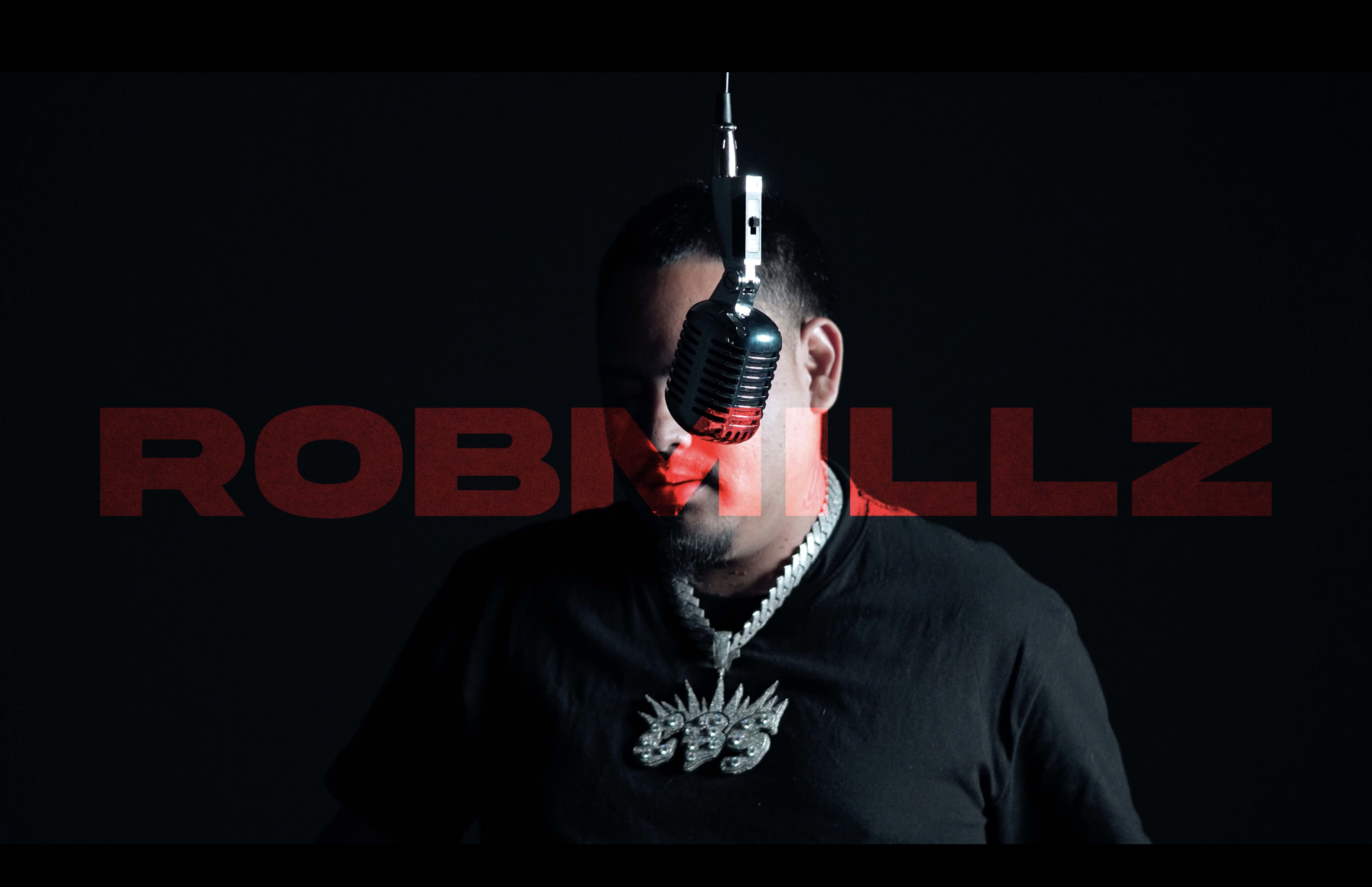 A man stands in front of a vintage microphone, with a large text overlay reading "ROBMILLZ" across the image.