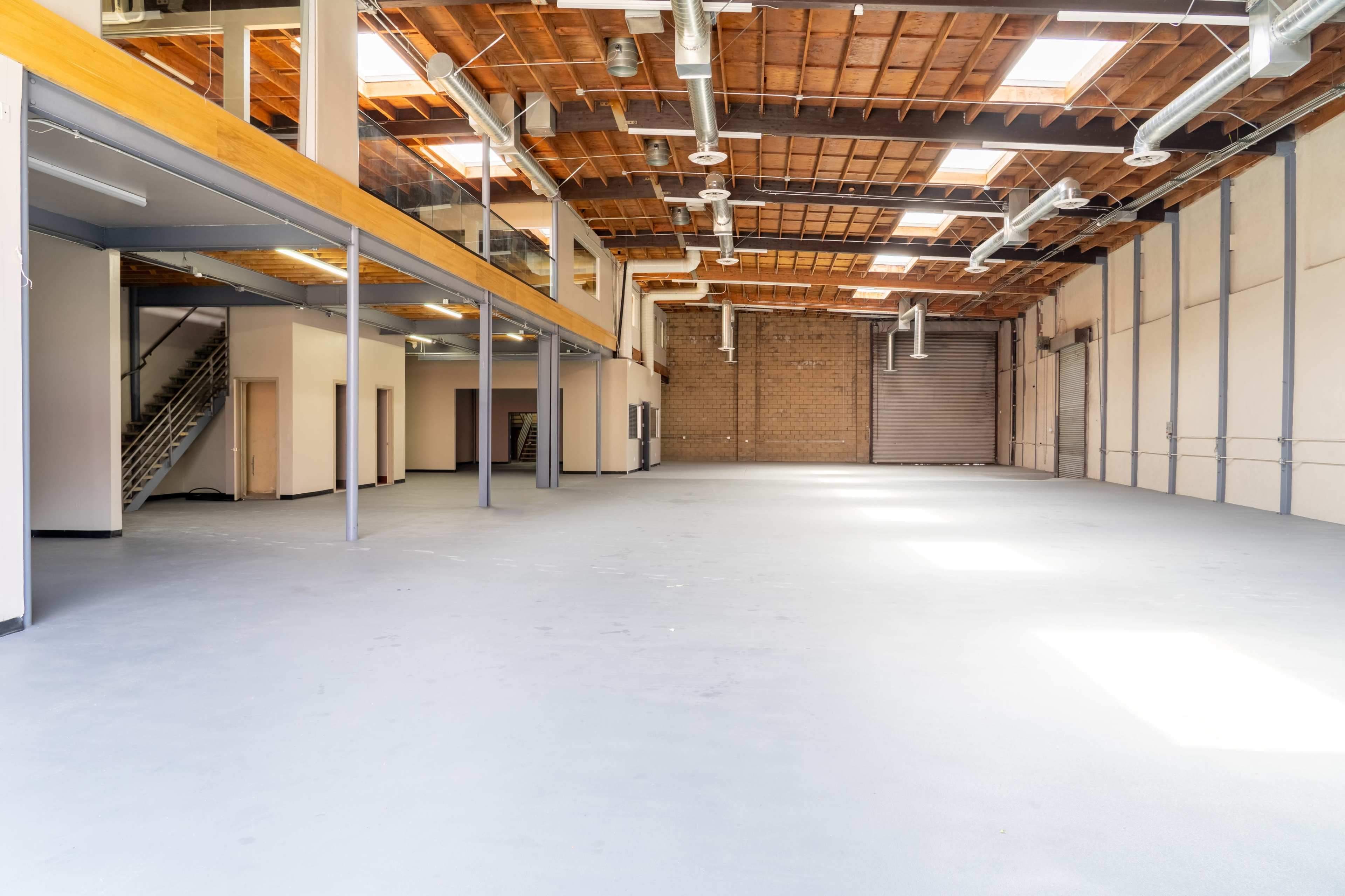The image shows a large, open industrial space with high ceilings, exposed beams, and concrete flooring.