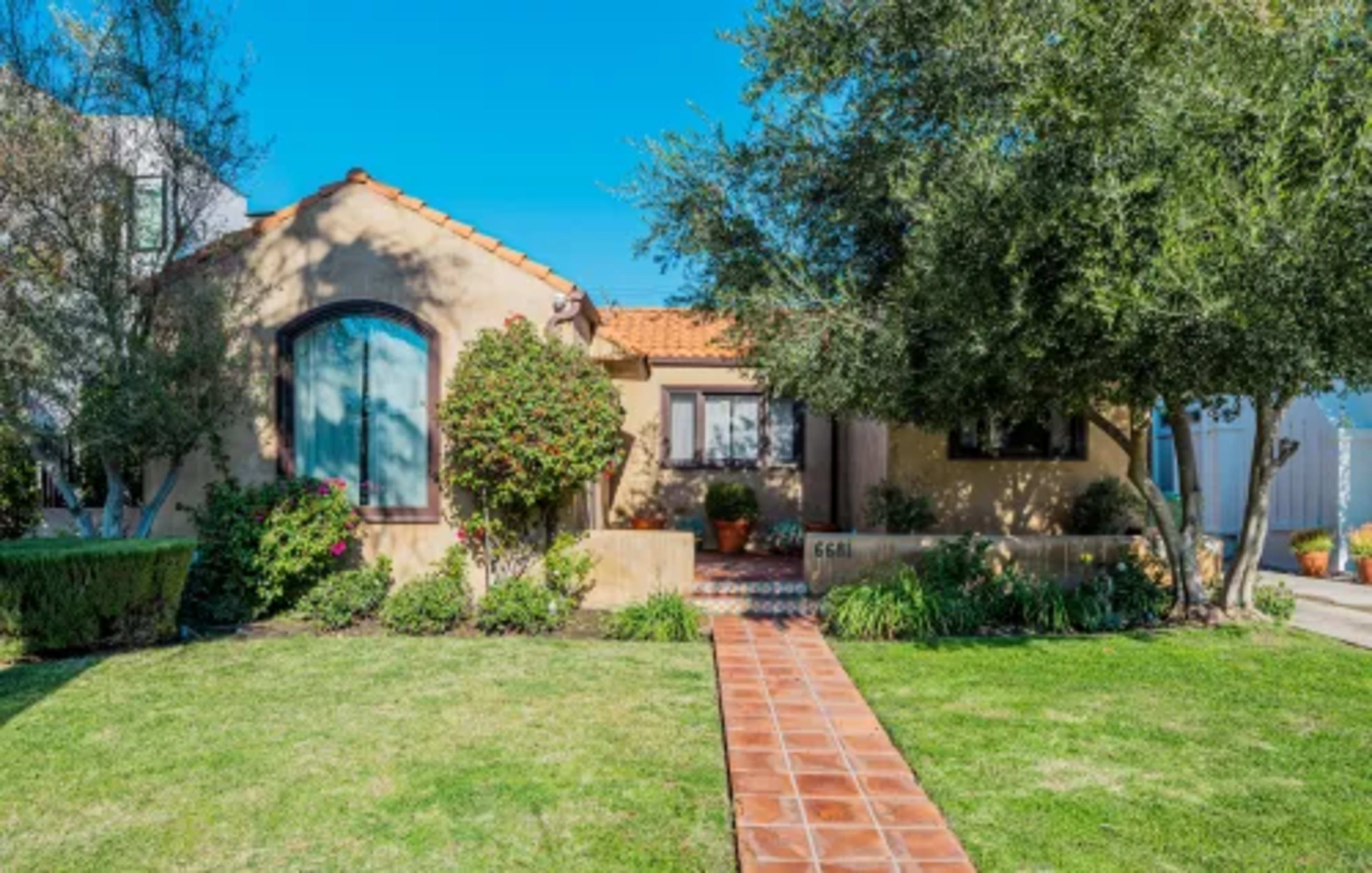 A single-story, stucco home with a tile roof and landscaped front yard.