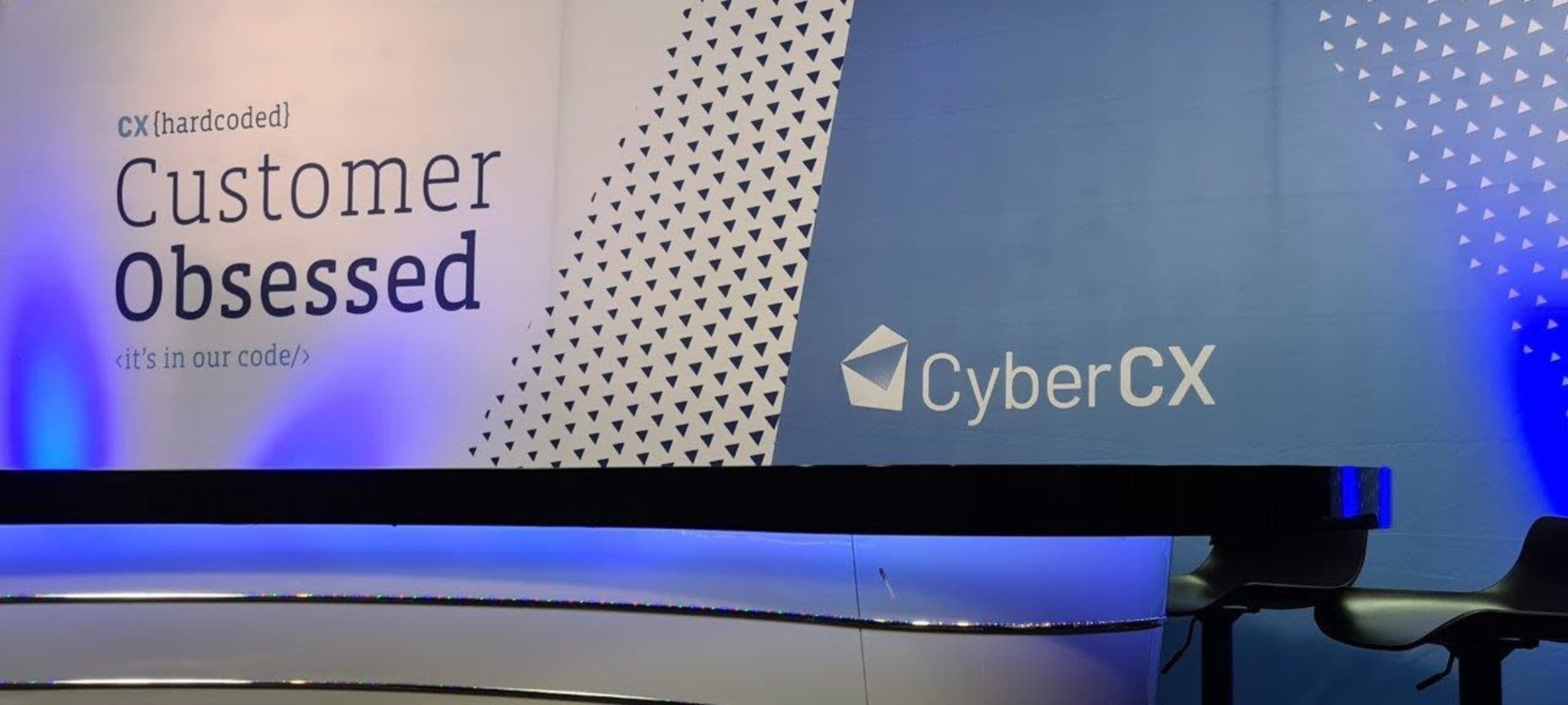 A conference stage backdrop with the text "Customer Obsessed" alongside the logo of CyberCX.