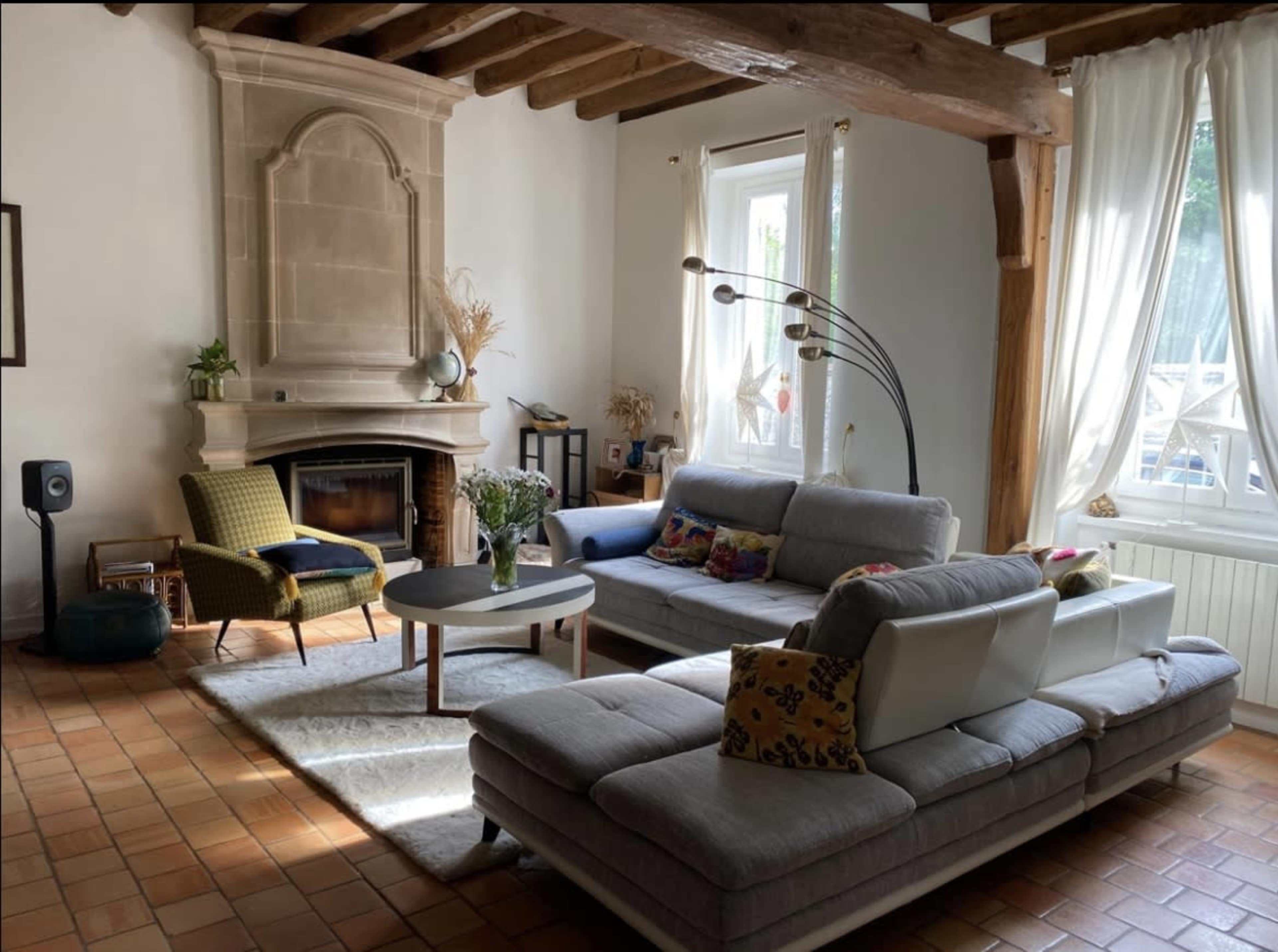 A living room with a fireplace, two sofas, a coffee table, and large windows letting in natural light.